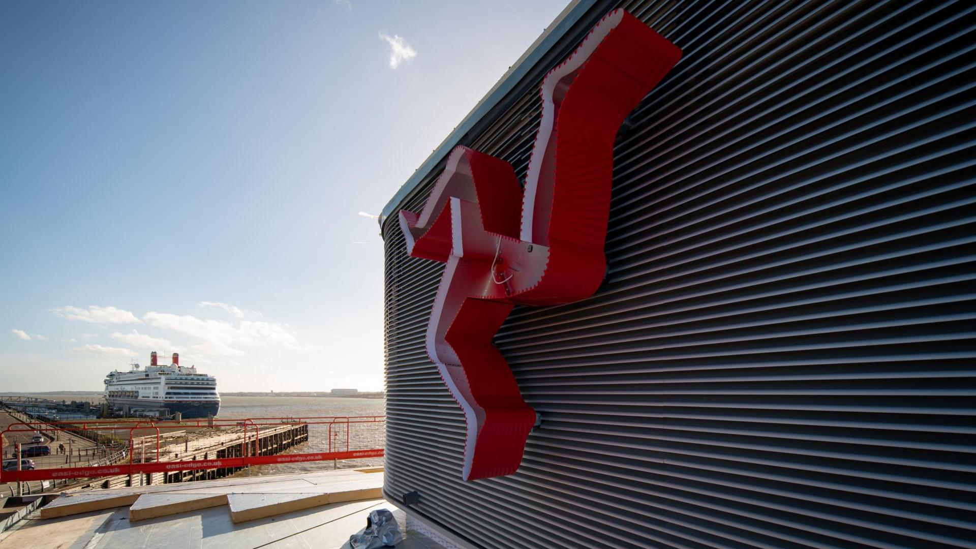 Three legs of man on the new Liverpool ferry terminal building