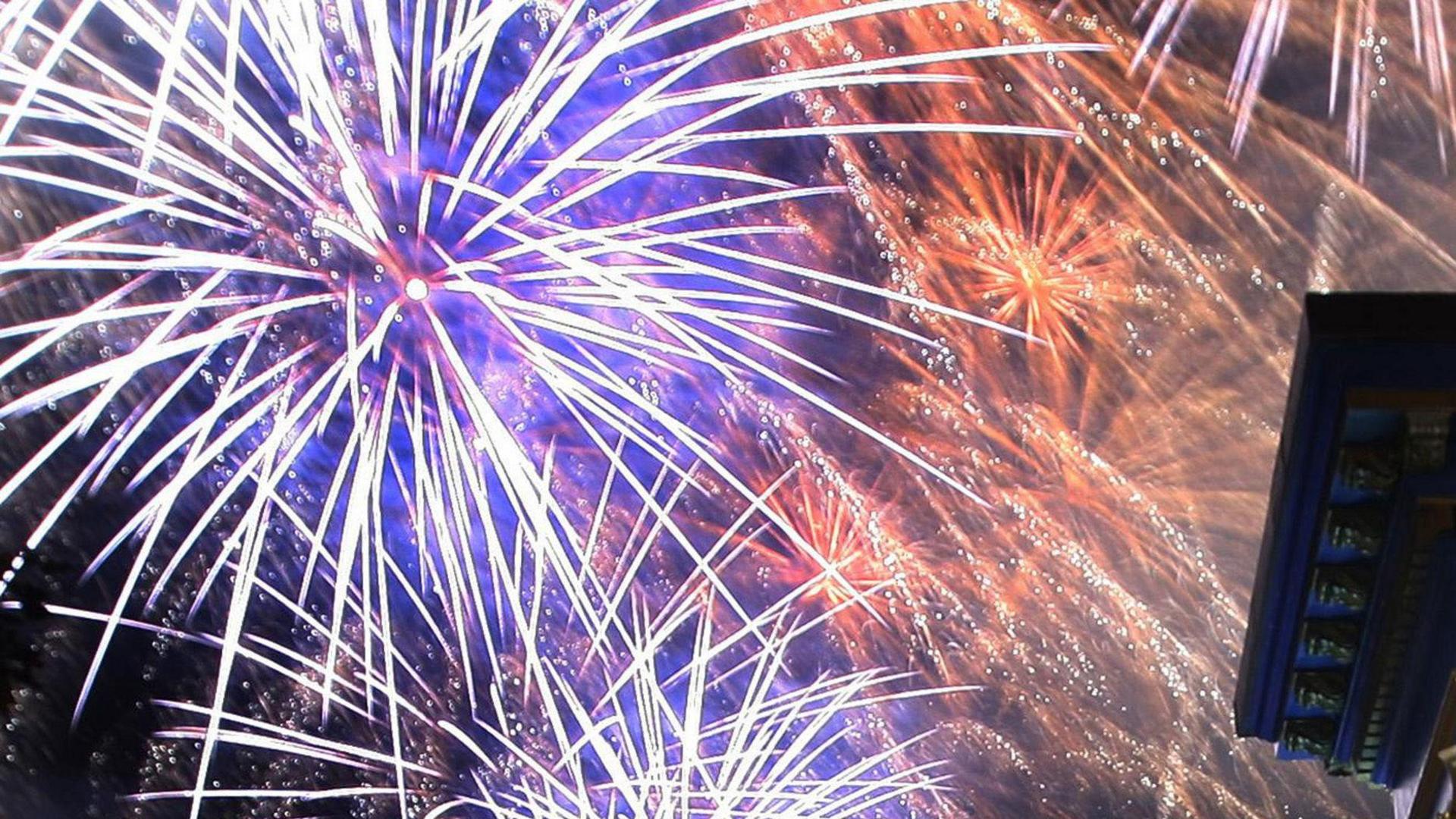 Bright purple and red fireworks exploding in the sky.
