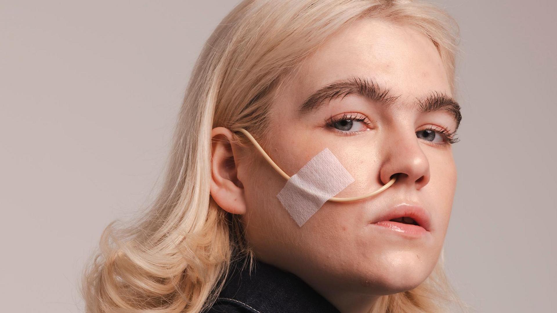 A portrait from the exhibition showing a model looking sideways at the camera, with a tube from her nose.