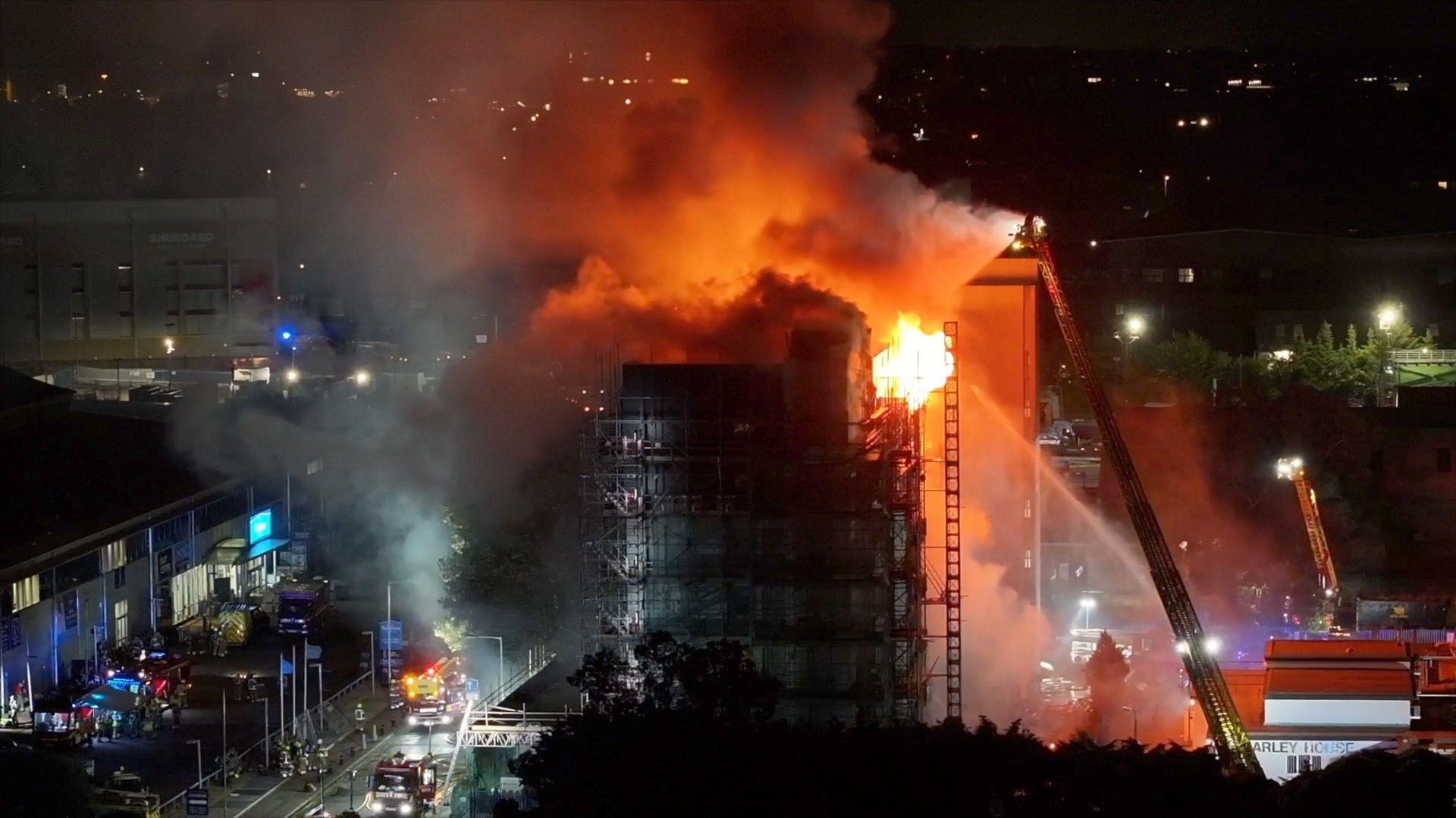 Building on fire with firefighter ladder raised up to it among residential houses