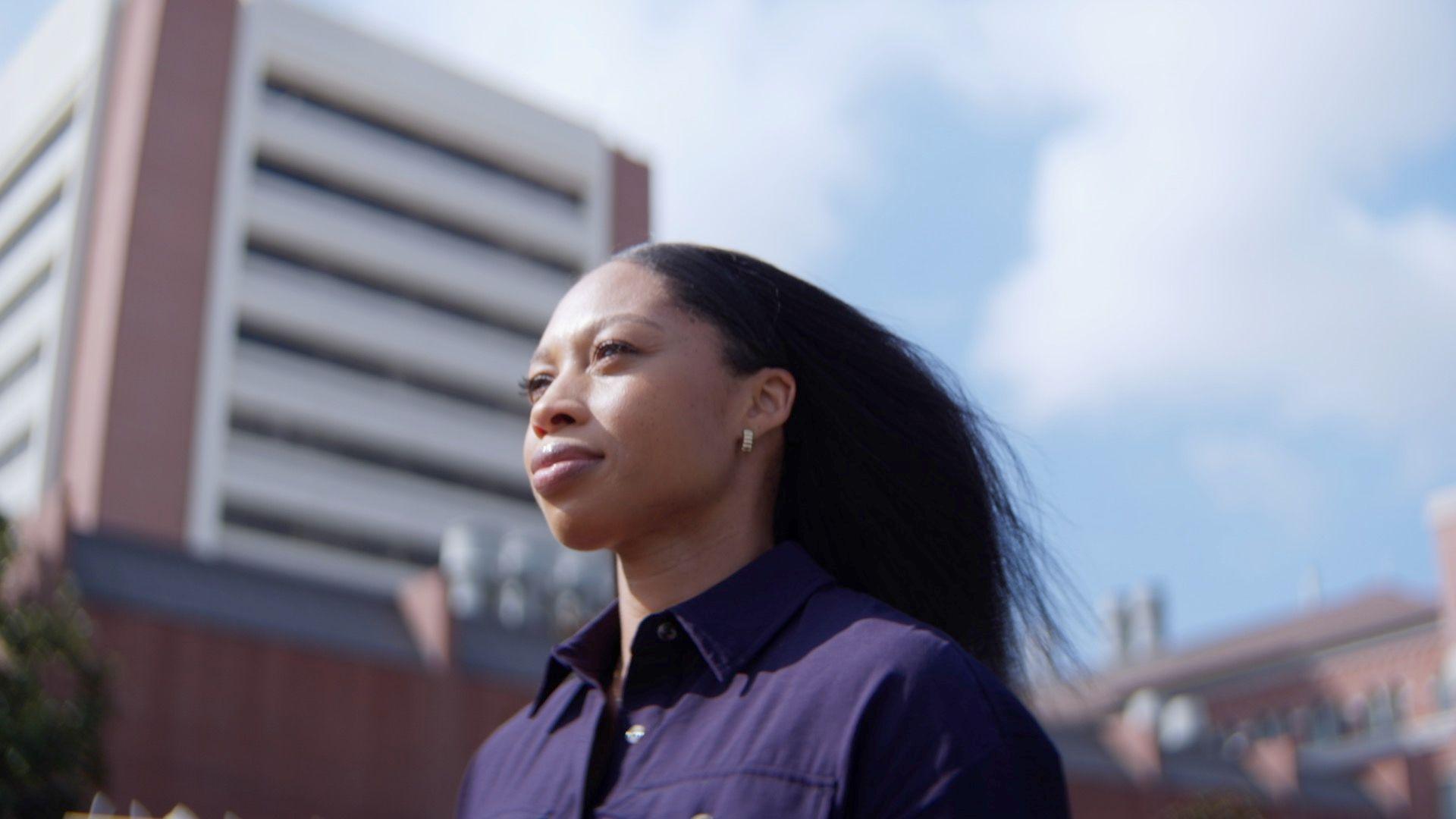 Image of Allyson Felix with a navy collared top and hair blowing in the wind