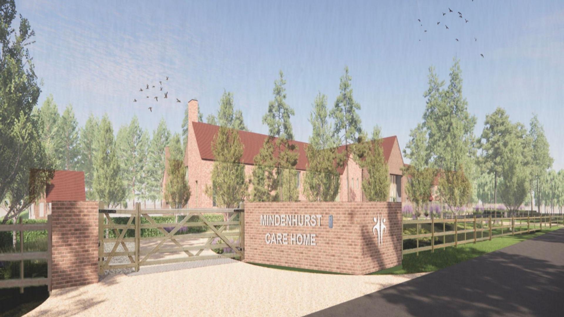 An artist's impression of the entrance to the Mindenhurst Care Home, showing the name on a wall beside a wooden gate and a wide driveway approaching the building,