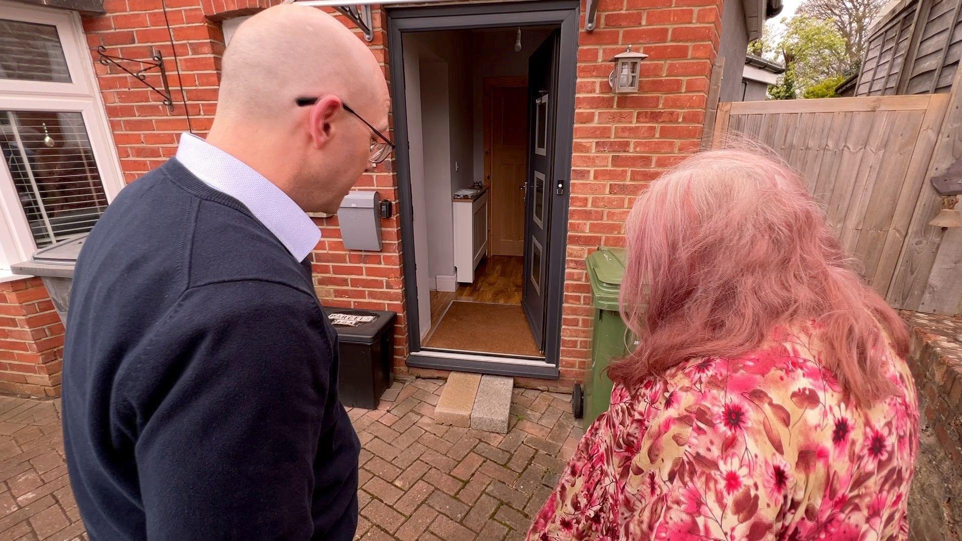 BBC reporter and Jan Shrapnell look at the breeze blocks outside her front door