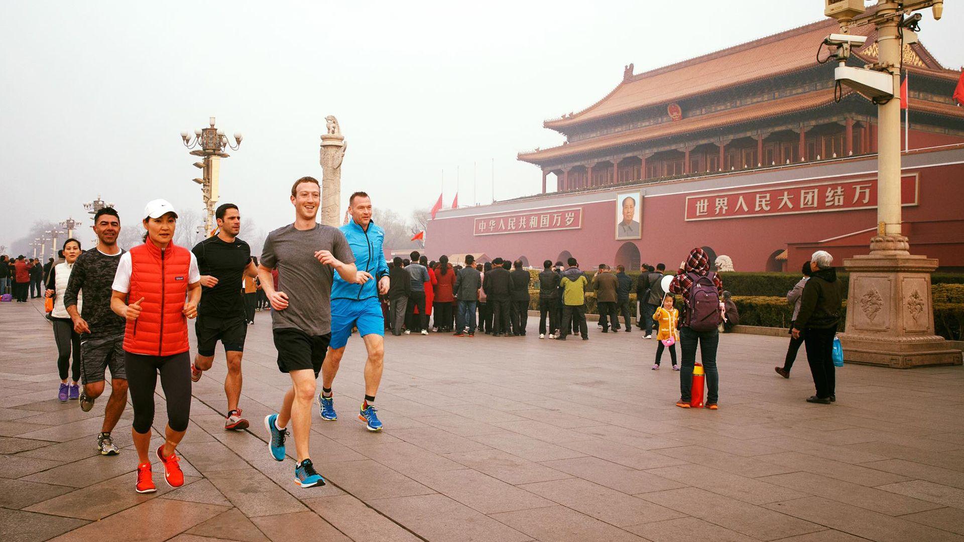 Mark Zuckerberg running in Tiananmen Square, Beijing, China. He is wearing a grey T-shirt and black shorts. And is accompanied by at least five other runners. The photo was first posted in 2016 on Mr Zuckerberg's social media.