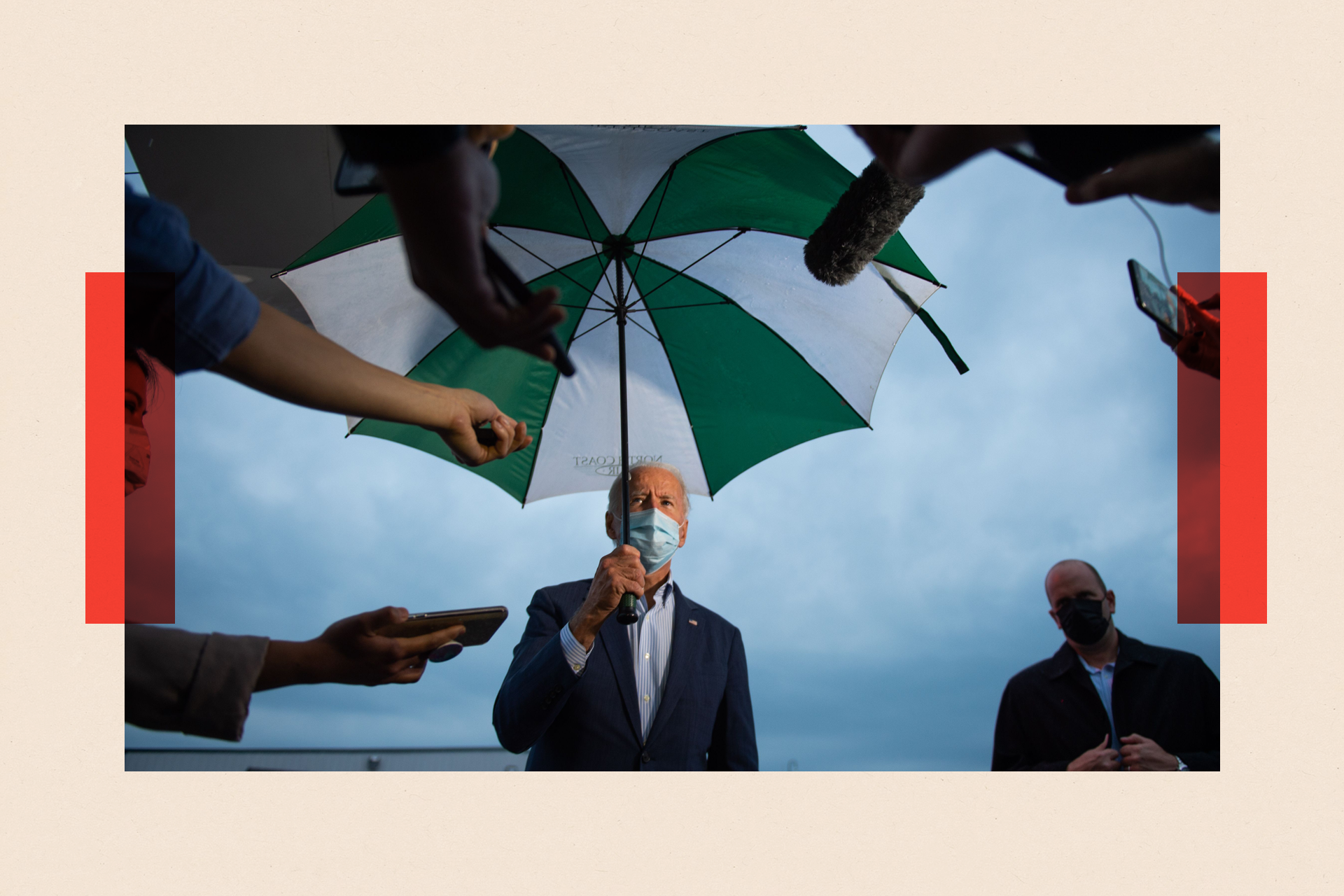 Joe Biden under an umbrella with a mask on, as press ask questions 