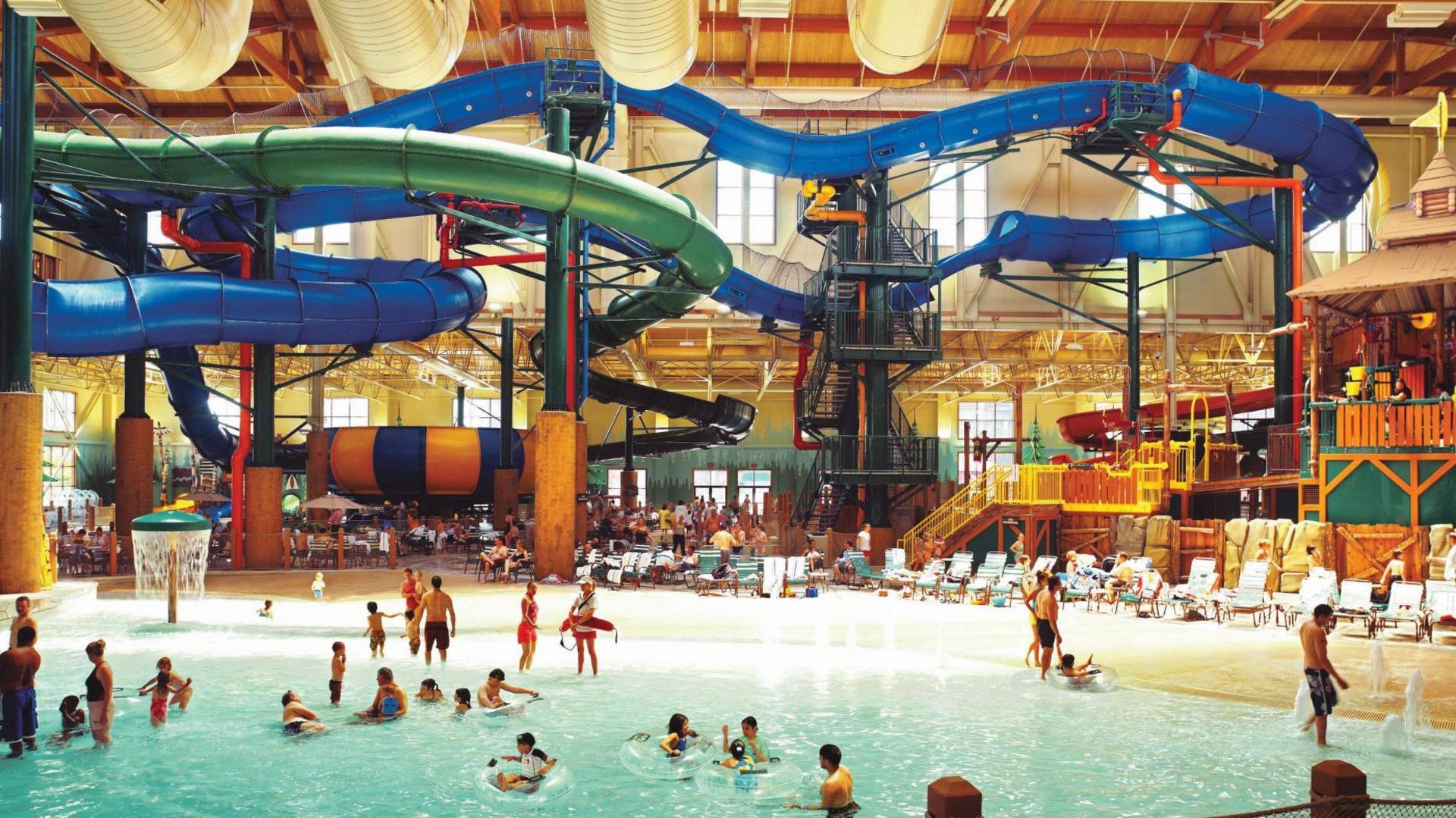 A large warehouse like indoor space with covered slides towering over a shallow pool
