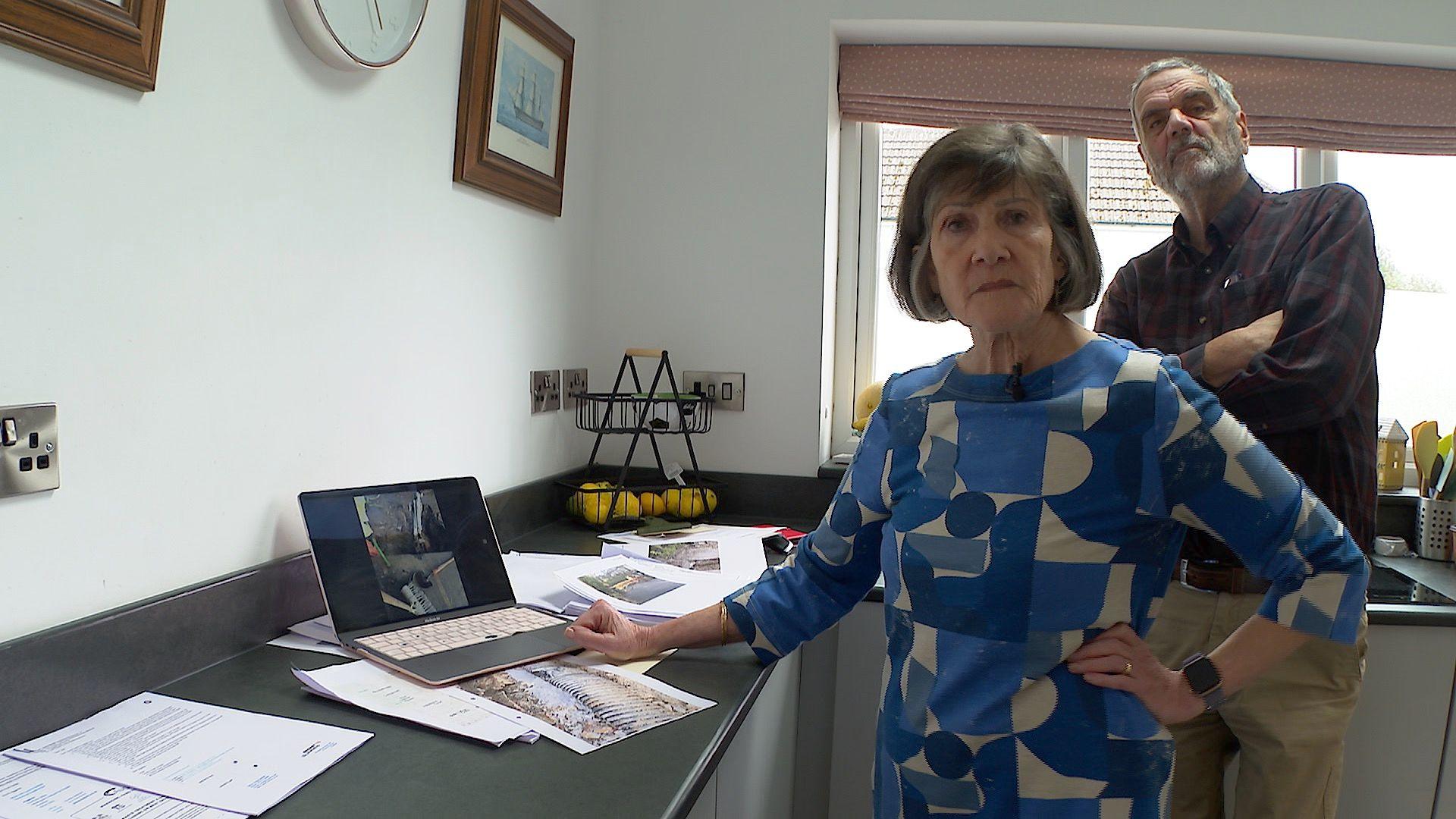 David and Anne Strobel standing together looking through photos of water damage