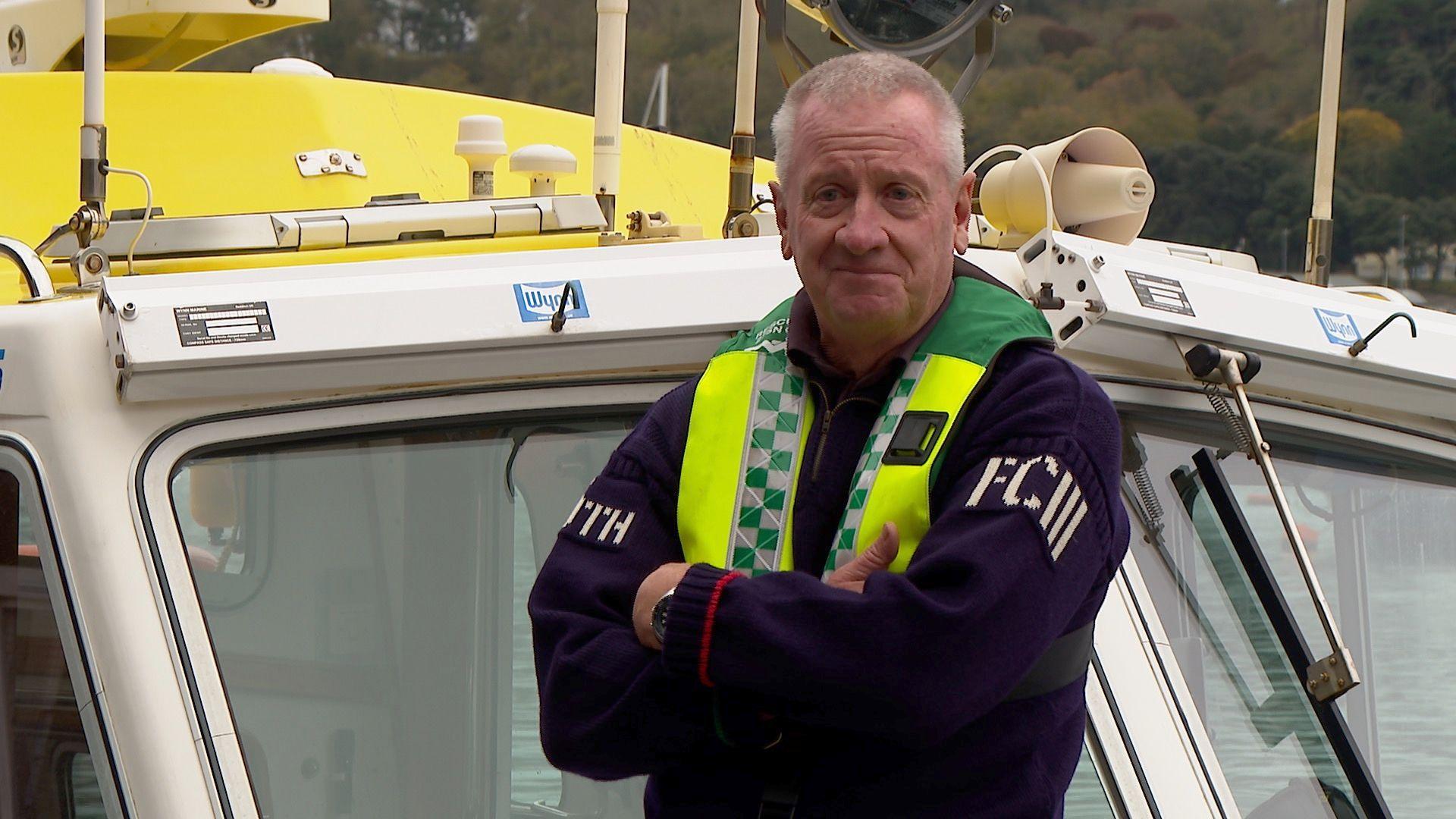 Man in a Guernsey stood near the bow of a boat