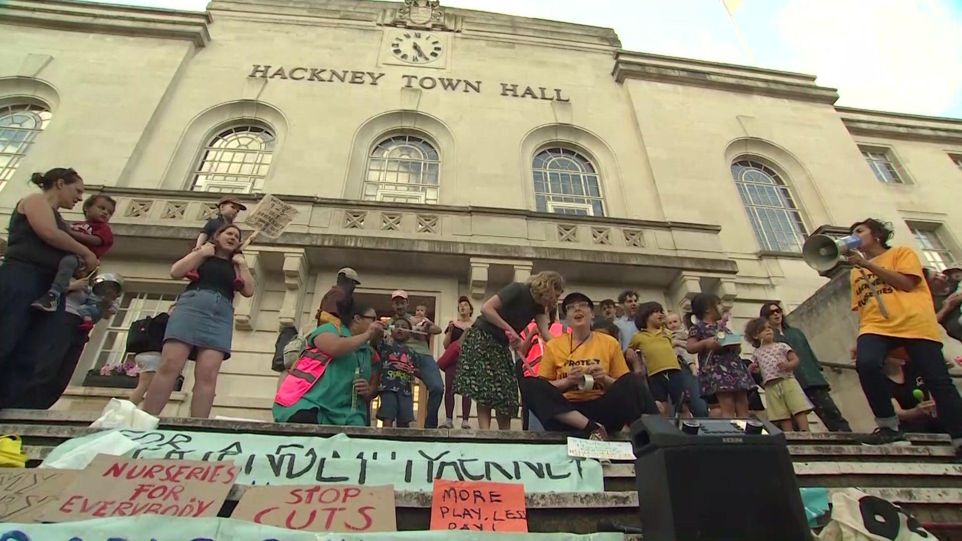 A group of protesters outside Hackney Town Hall to protest against the cuts, there are banners that say "stop cuts" and "nurseries for everybody"