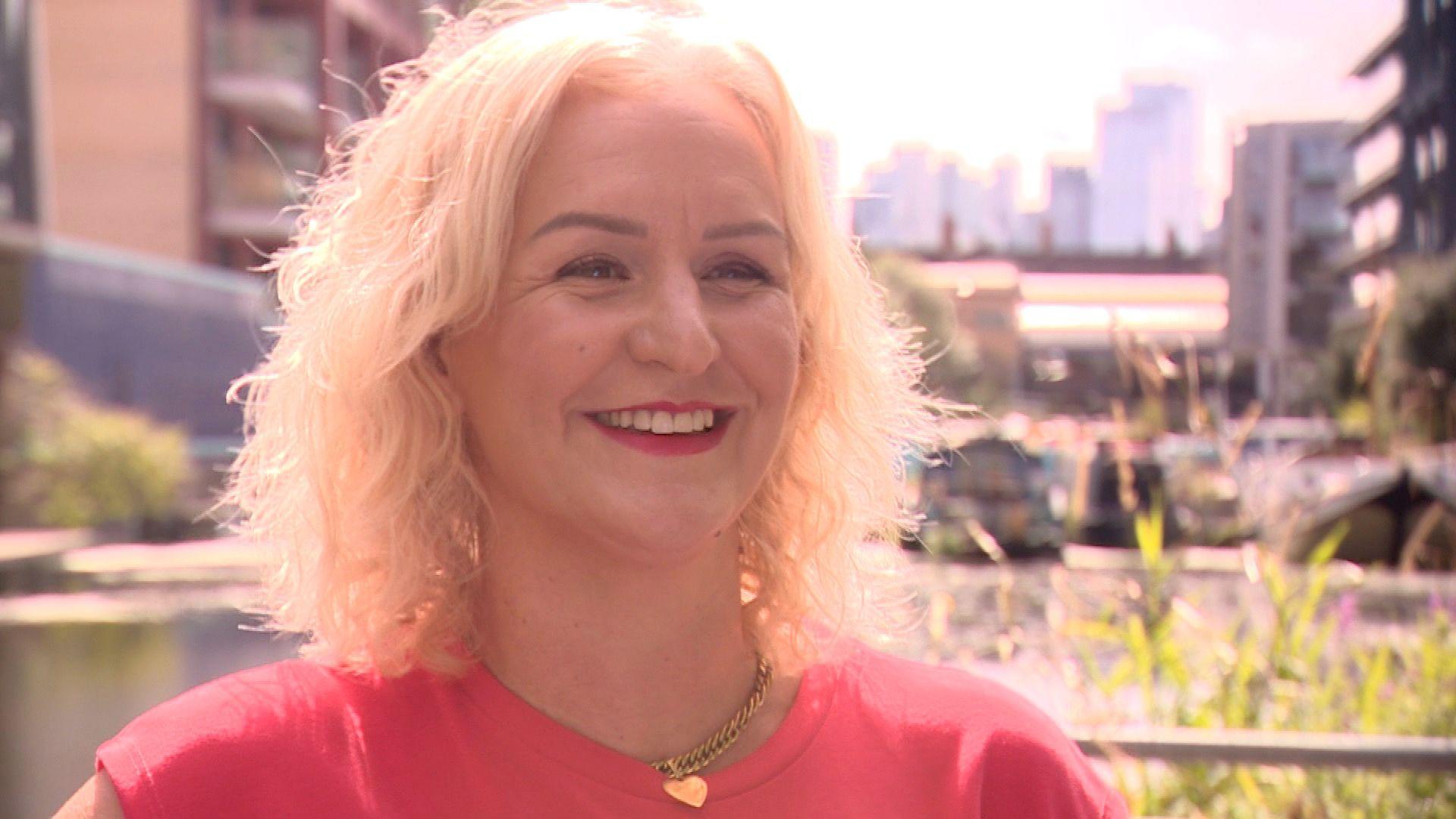 Jo in a red dress standing outside with the City of London in the background