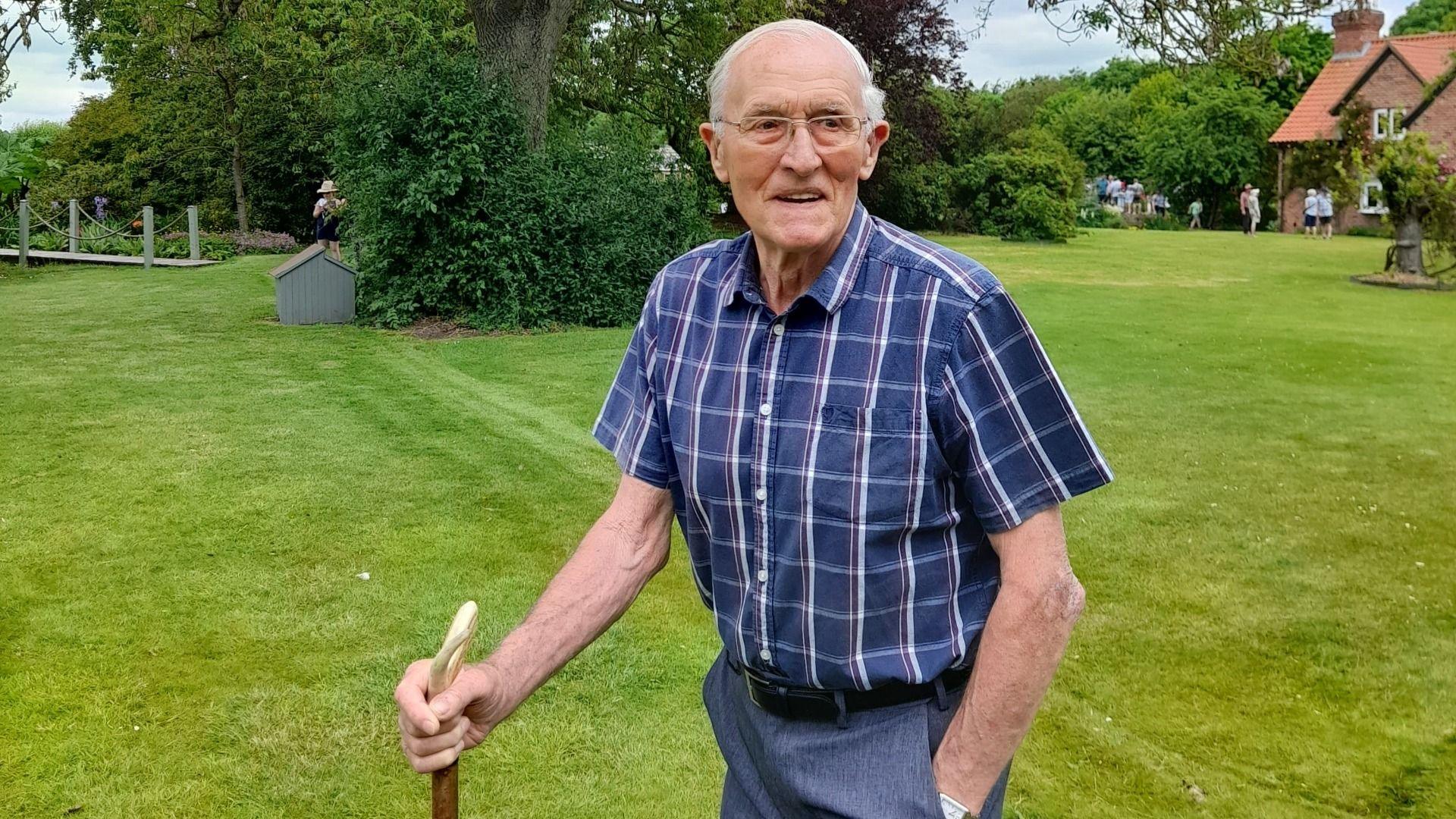 Richard Byas in a garden with a walking stick.