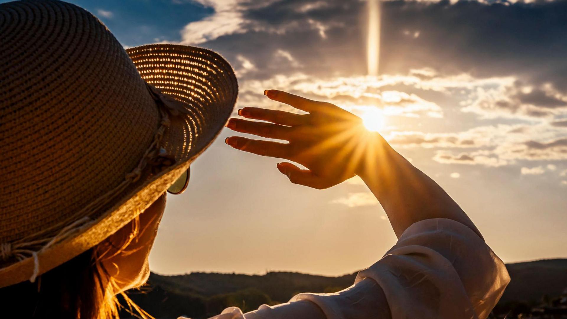 Lady in sunhat shielding from sun 