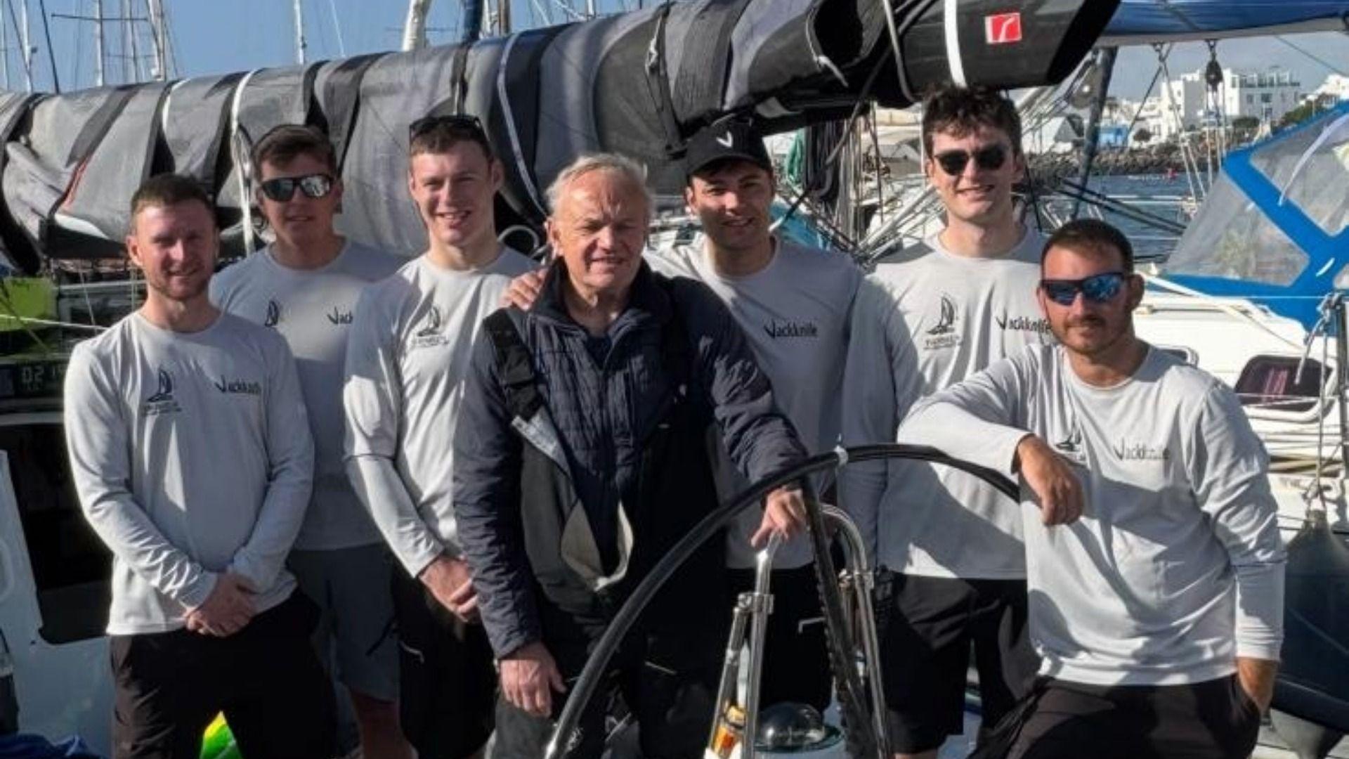 Llun o'r saith o ddynion, criw y cwch Jackknife yn sefyll o flaen y cwch cyn y ras