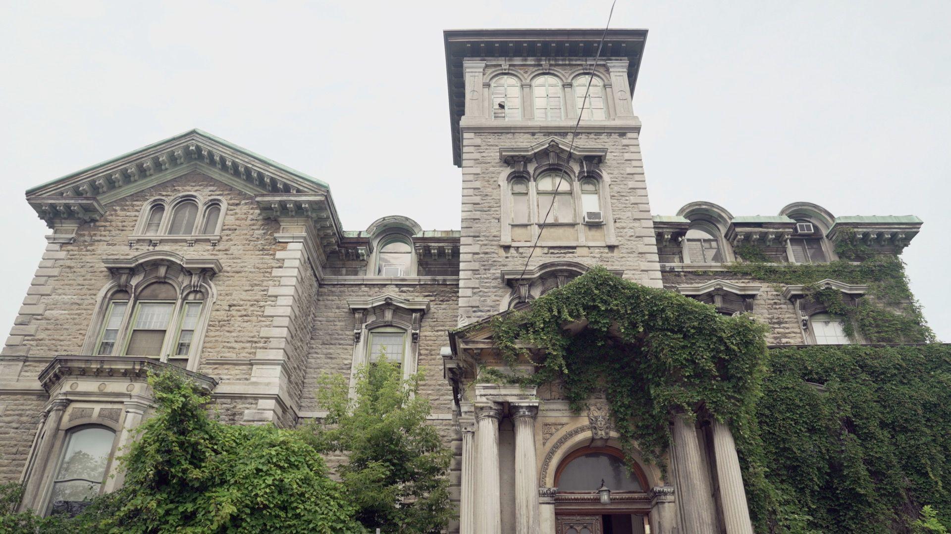 The facade of the Allan Memorial Institute, an old stone mansion overrun with deep green ivy.
