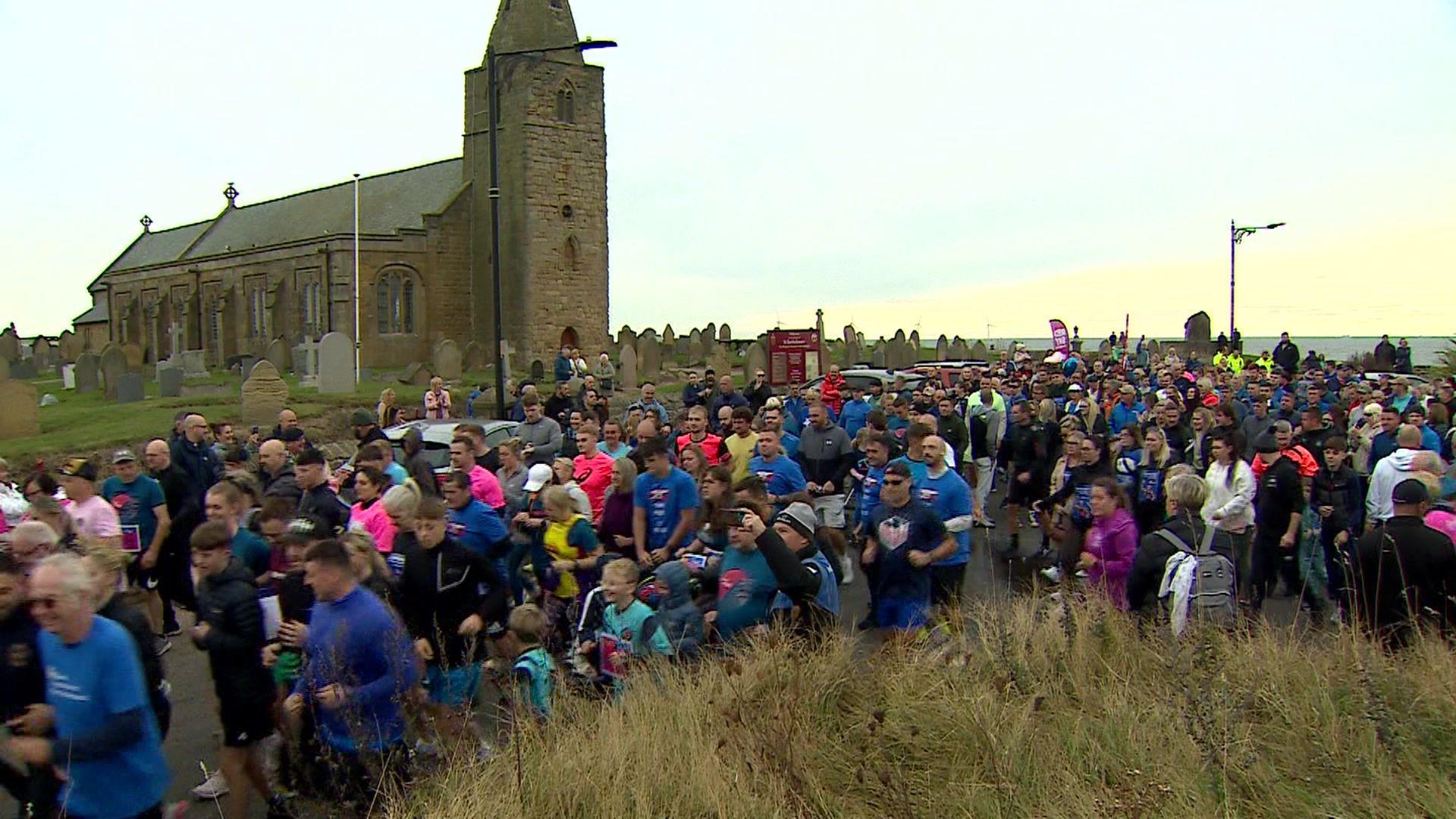 Hundreds of people are running as a group past a church