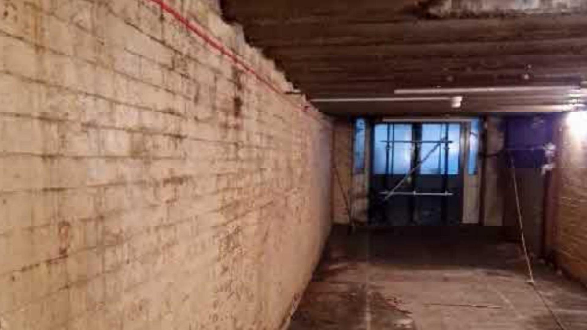 The inside of a white brick tunnel in a rundown state