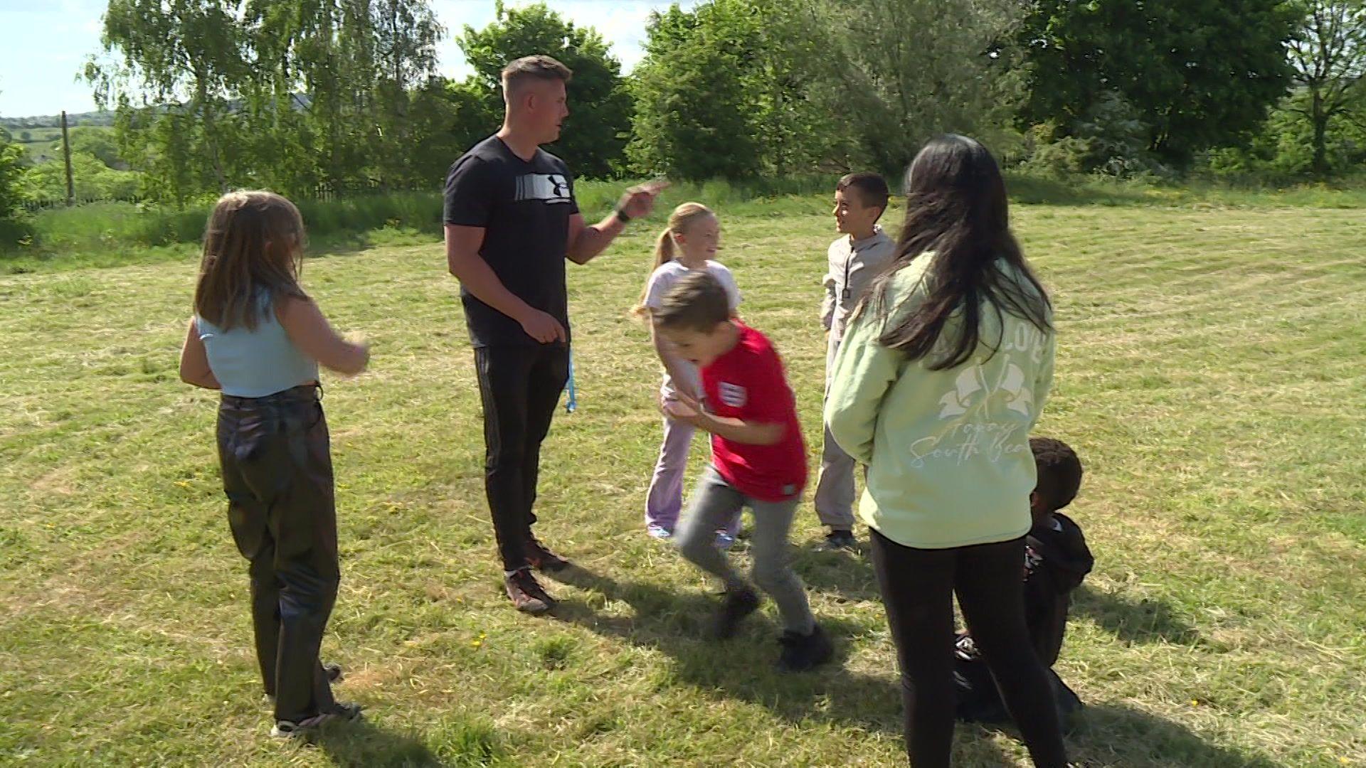 Man teaching children outside on the grass