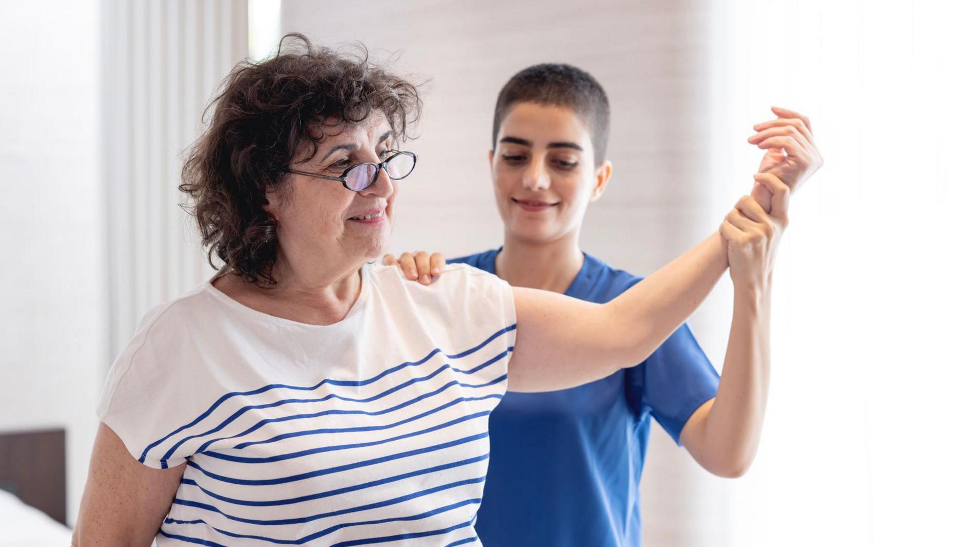 A health worker helping massage a patient's arm.