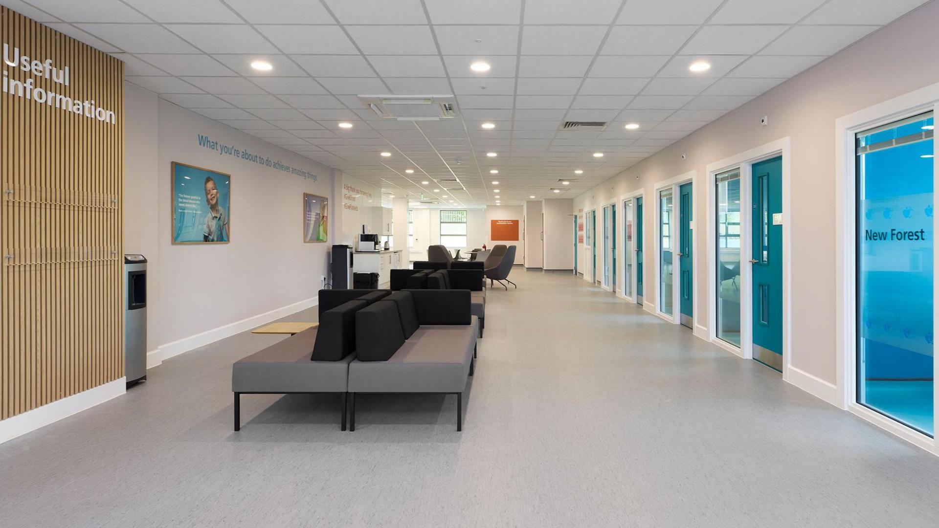 A large waiting room with comfortable sofas and chairs. Several doors lead off into consultation rooms.