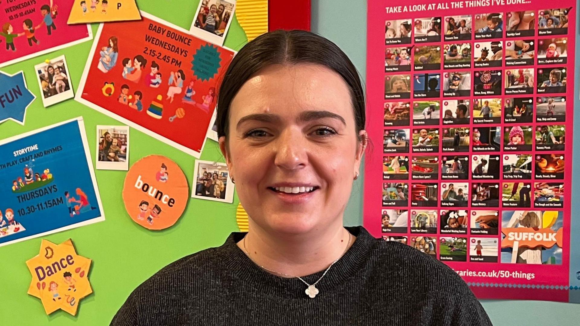 Sophie Vendenbrink-Budgen smiles at the camera. She has dark hair that is slicked back behind her head. She wears a black jumper with a necklace around her neck.