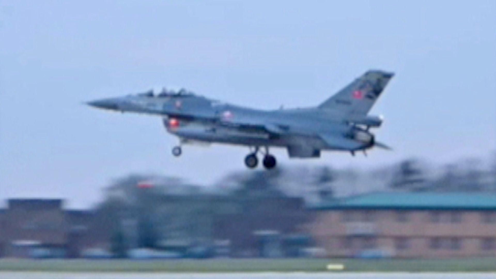 A grey fighter jet in action flying low into RAF Waddington air base.