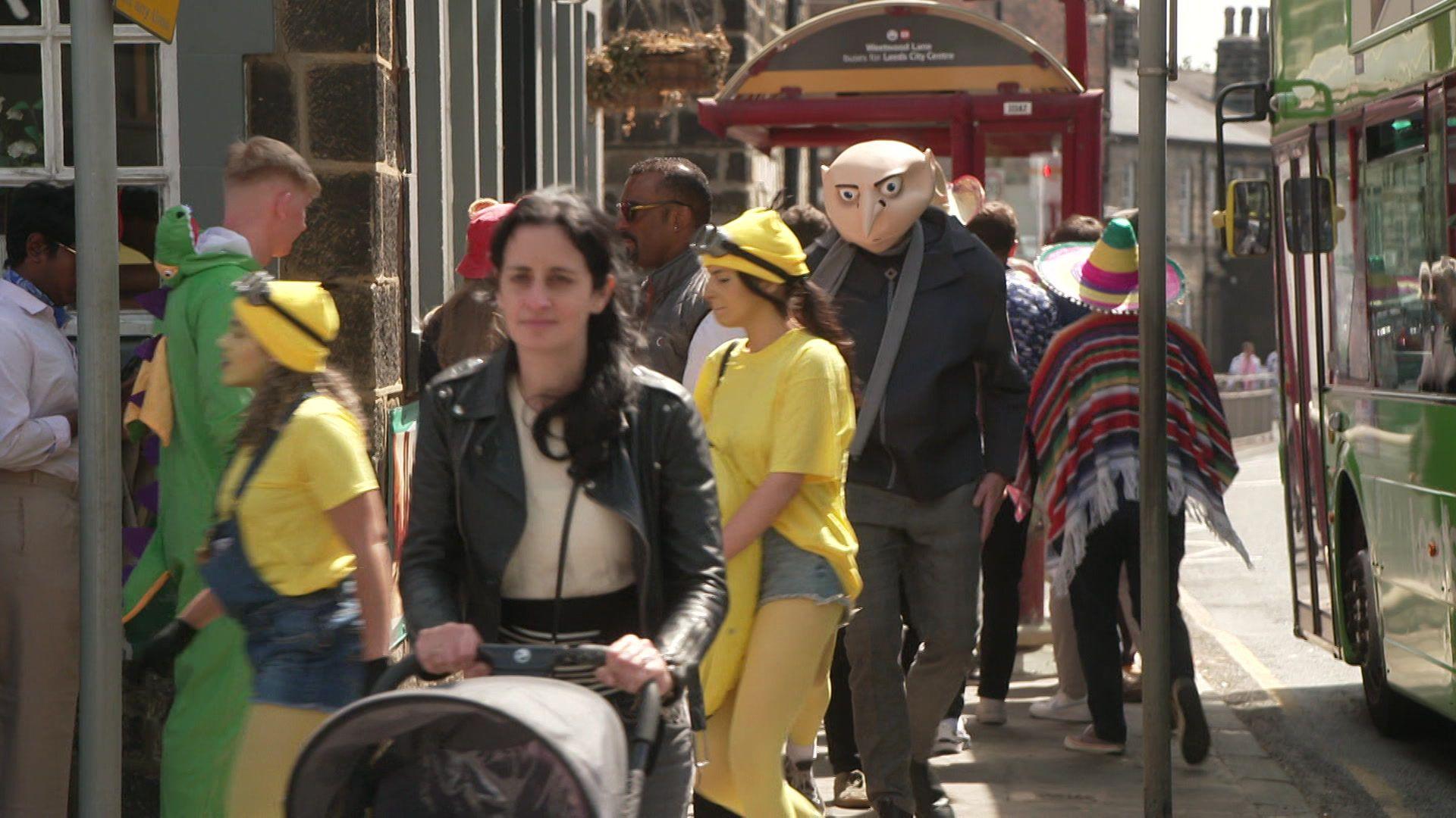 A woman pushes a pram while Gru, from the Minions film, walks behind her