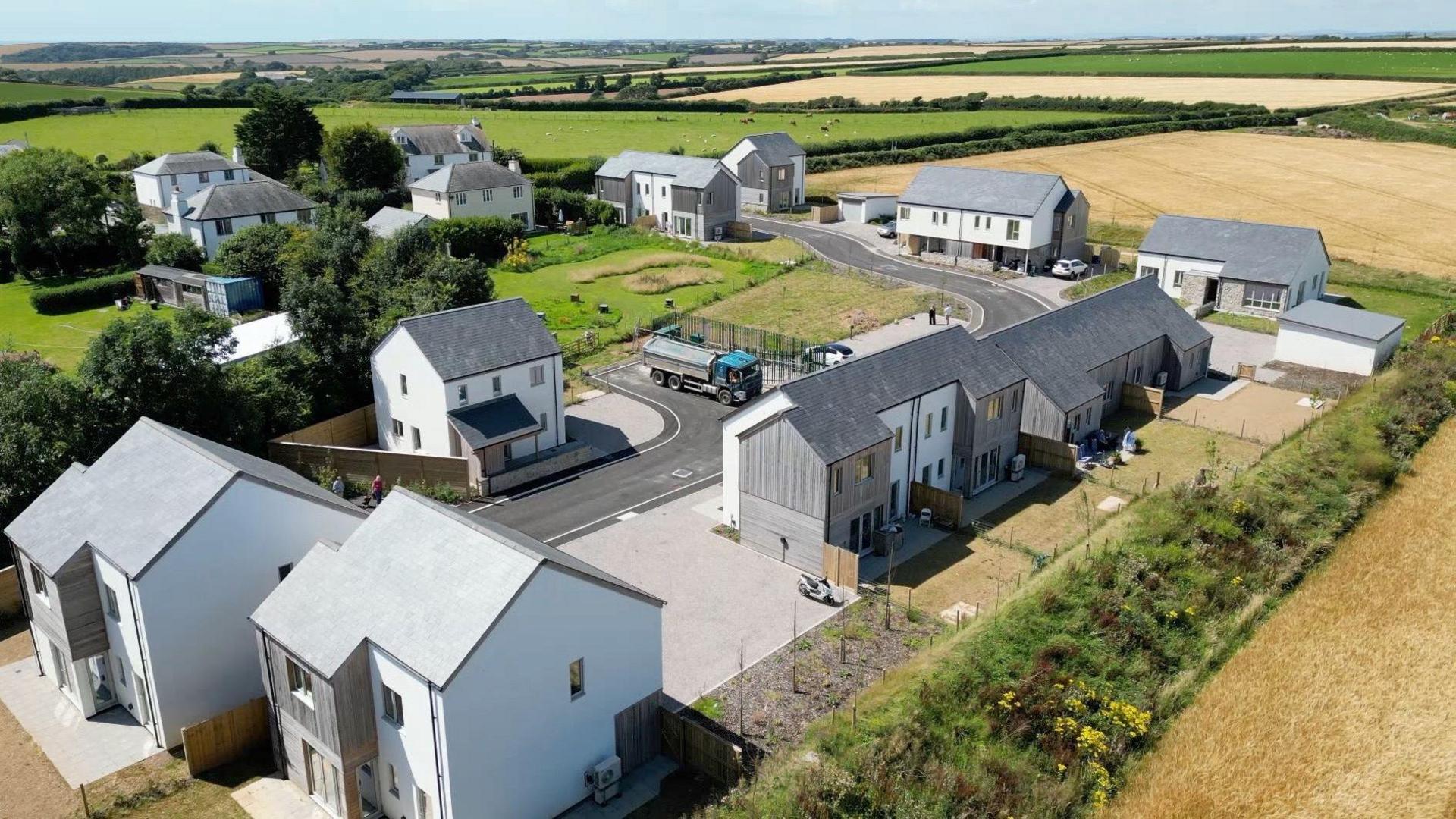 Aerial view of green fields showing a small new housing estate in St Ann's Chapel containing eight affordable homes and three homes for sale on the open market