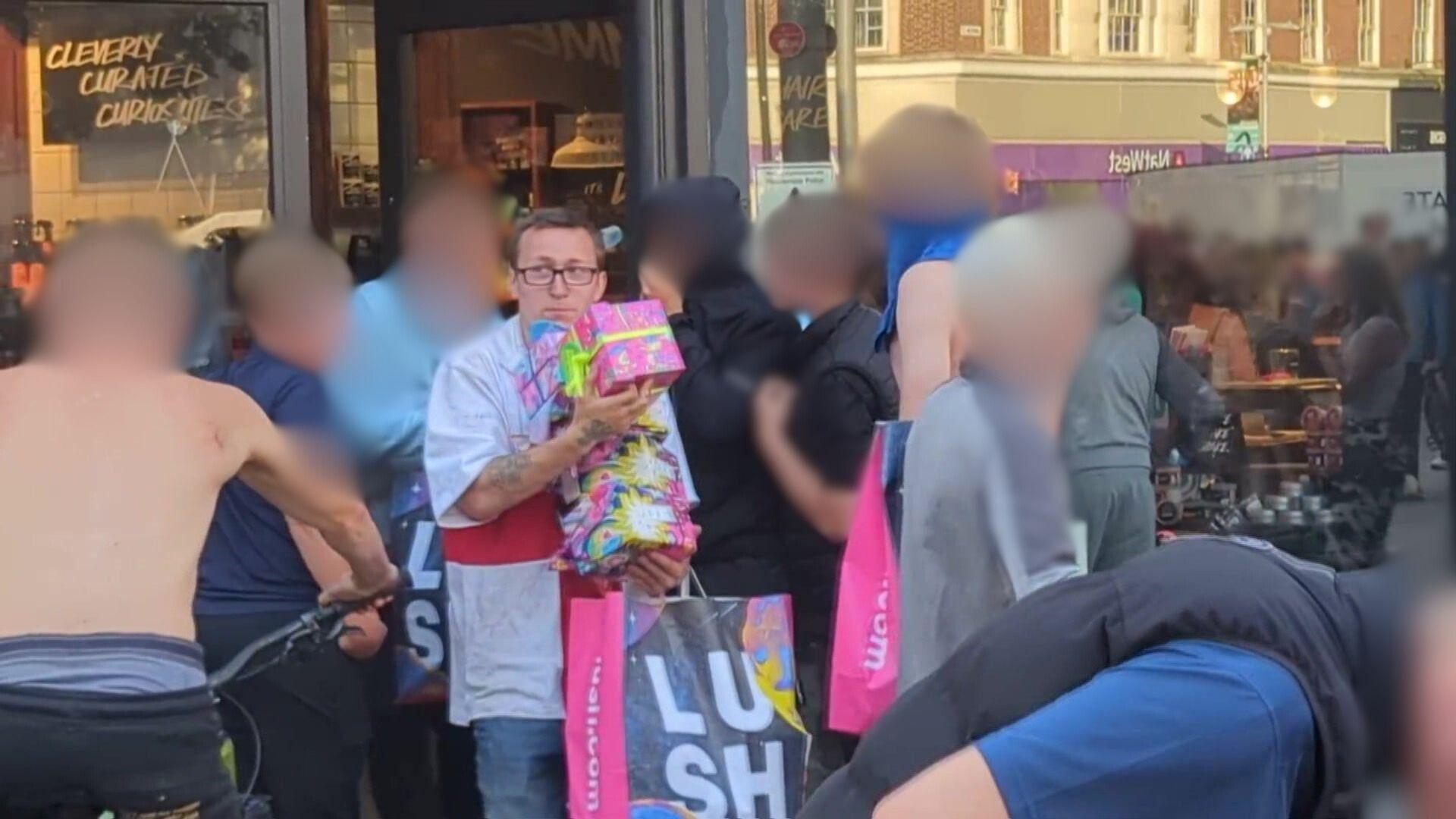 John Honey walks out of the Lush cosmetics store in Jameson Street carrying boxes and carrier bags. He is wearing a shirt depicting the St George Cross and is wearing glasses. Honey is surrounded by several other people who were also involved in the disorder.