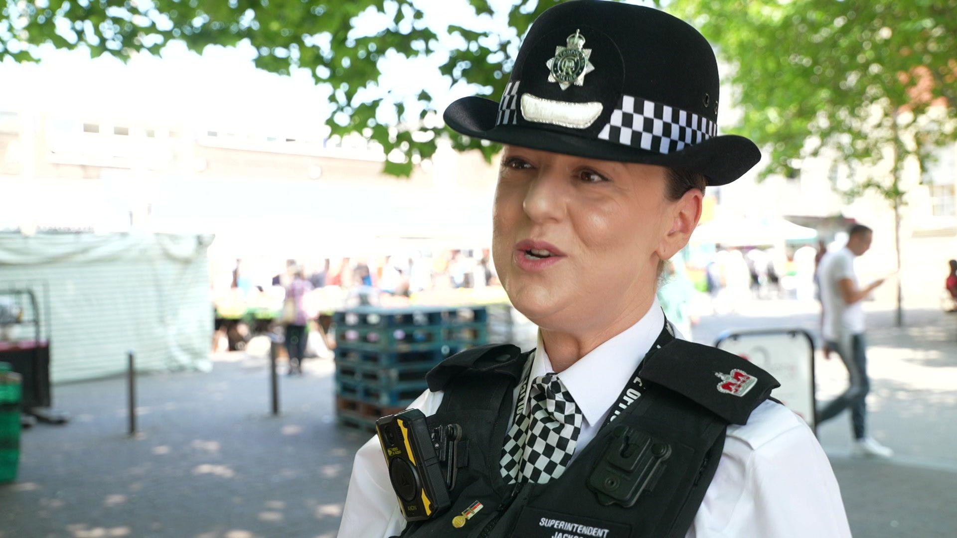 Supt Sarah Jackson standing on a paved area, wearing a police officer's helmet and uniform, with black padded vest and white shirt.