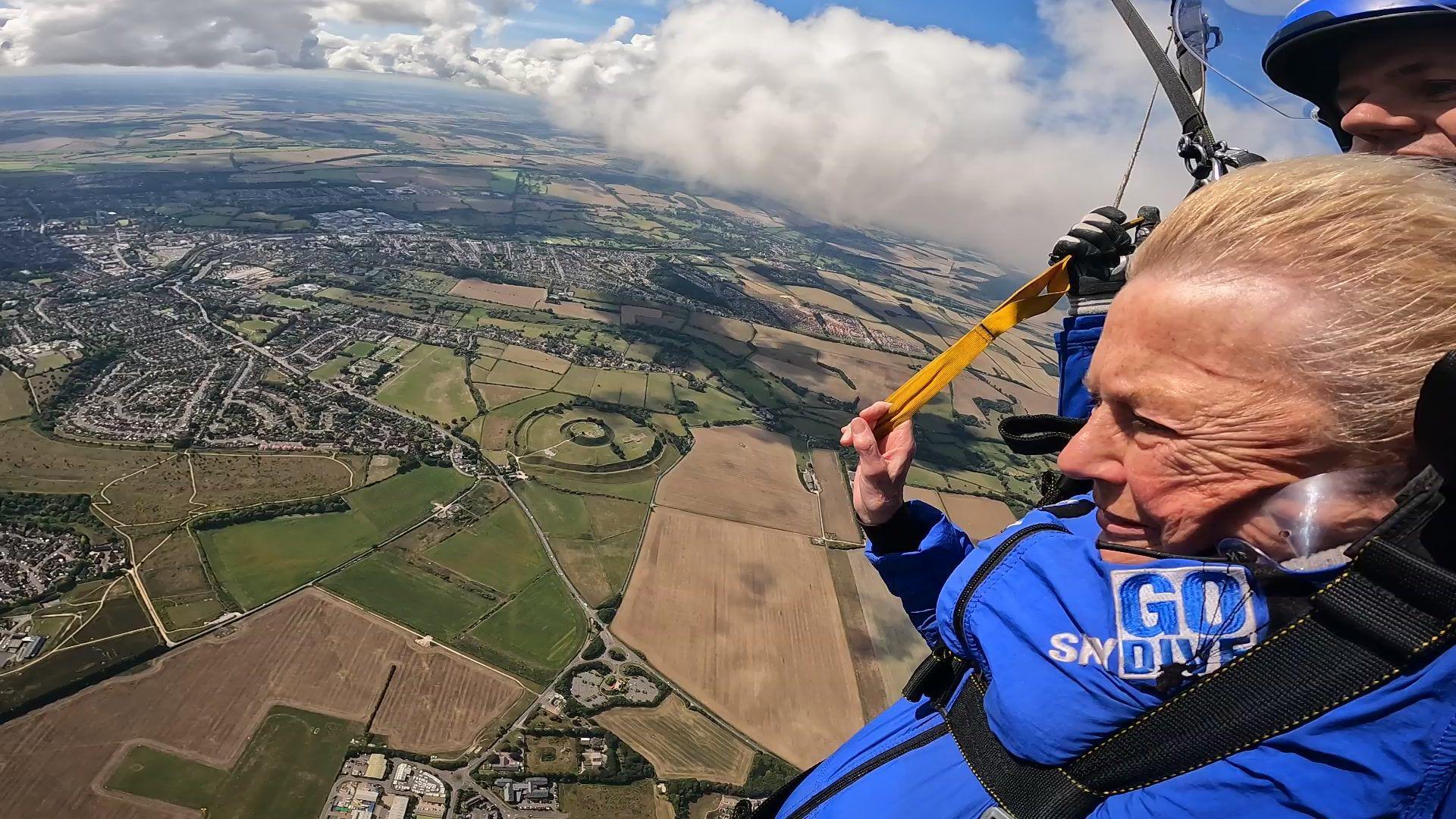 Terri Collins undertaking tandem skydive with backdrop of Wiltshire countryside behind her