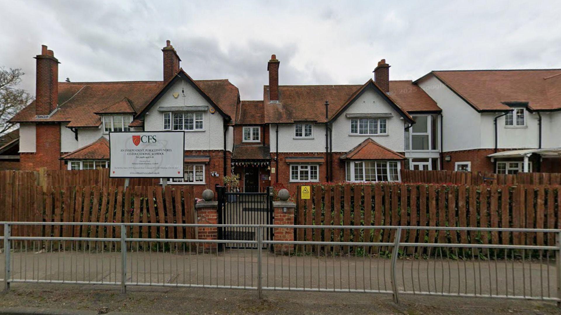 A Google Street imaghe of a two-storey white and red brick building with a wooden fence separating it from the path. There is a sign which says "CFS" on it.