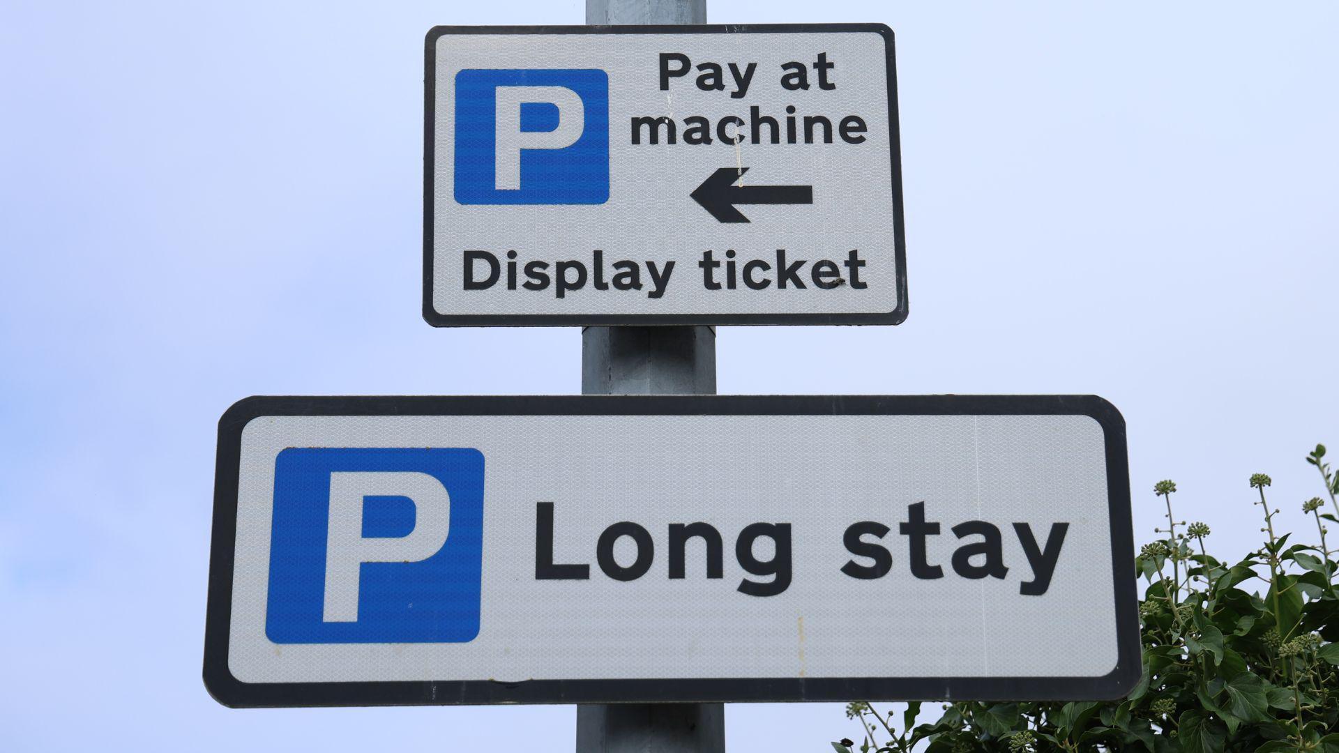 A white parking sign reading 'Pay at machine', 'Display ticket' and 'Long stay'. 