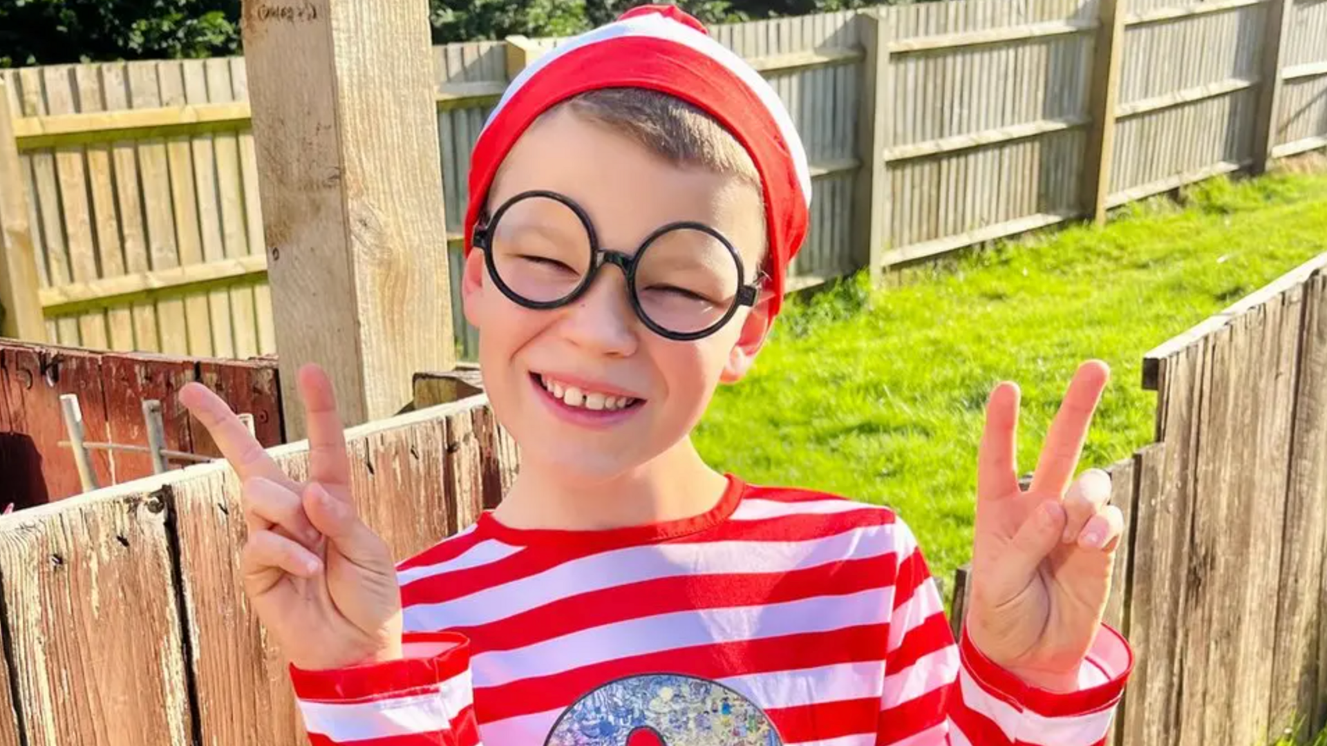 A boy in a stripy t-shirt and stripy hat and black-rimmed glasses