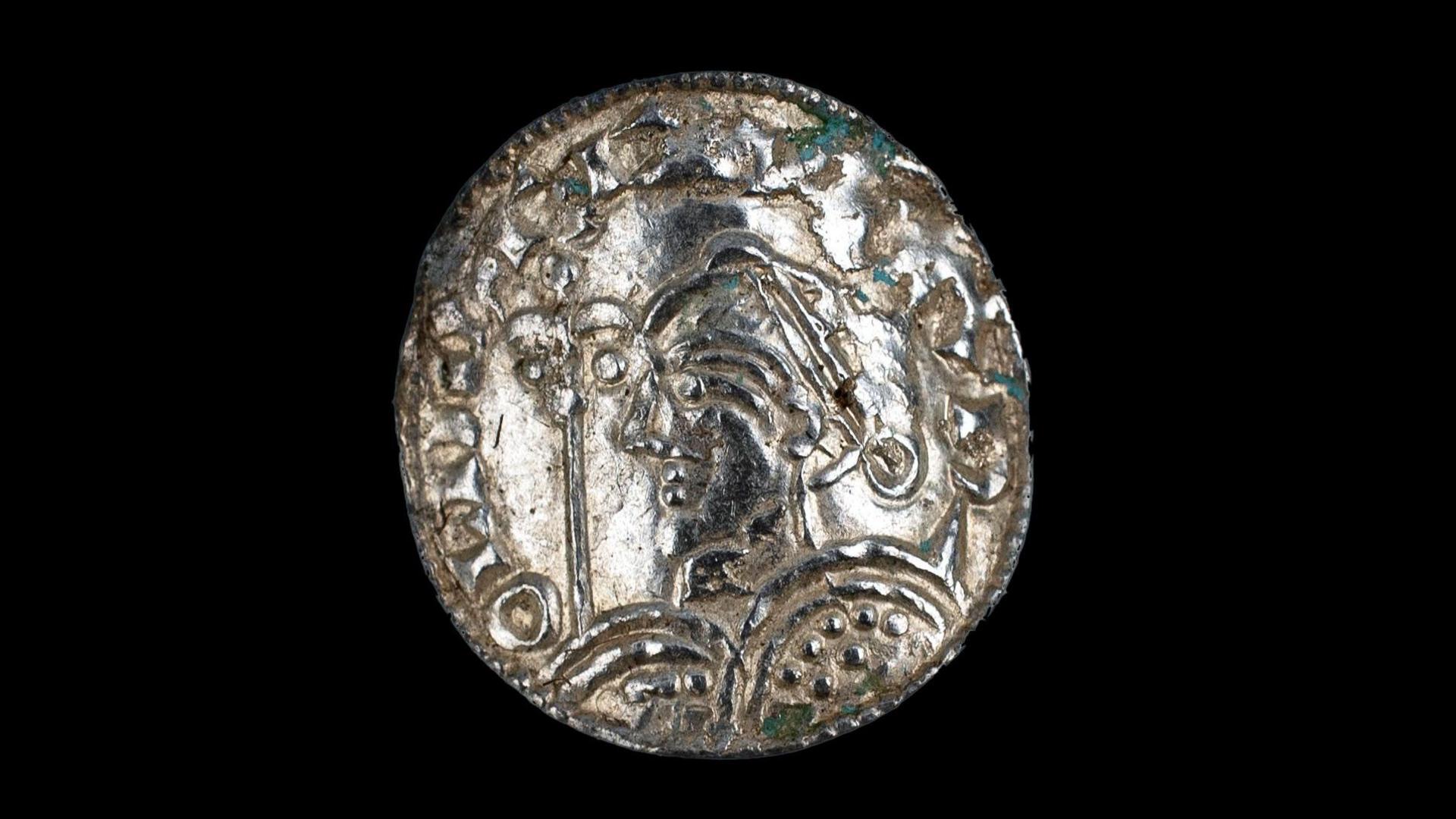 A close-up image of one of the silver coins, which appears to have been cleaned, set against a black background.