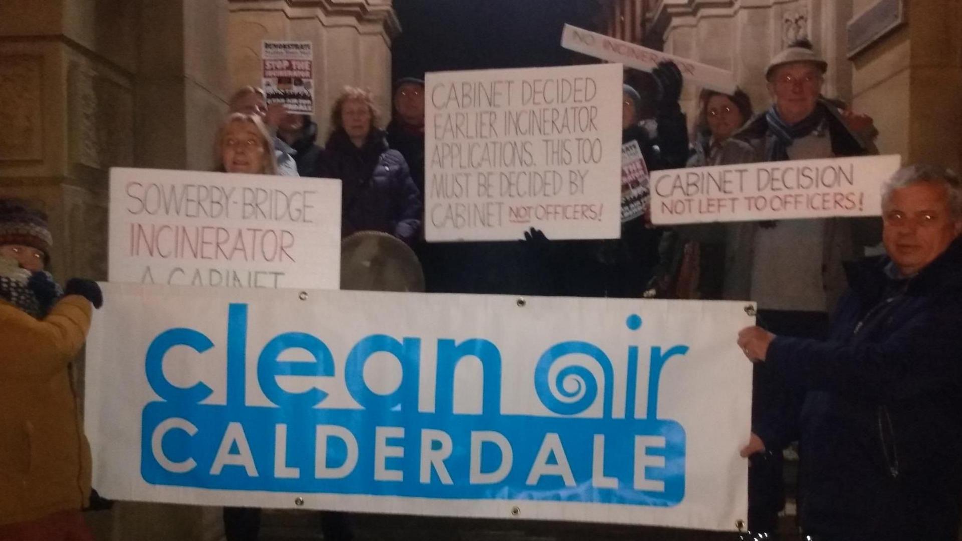 Group of protestors holding banners outside a council door