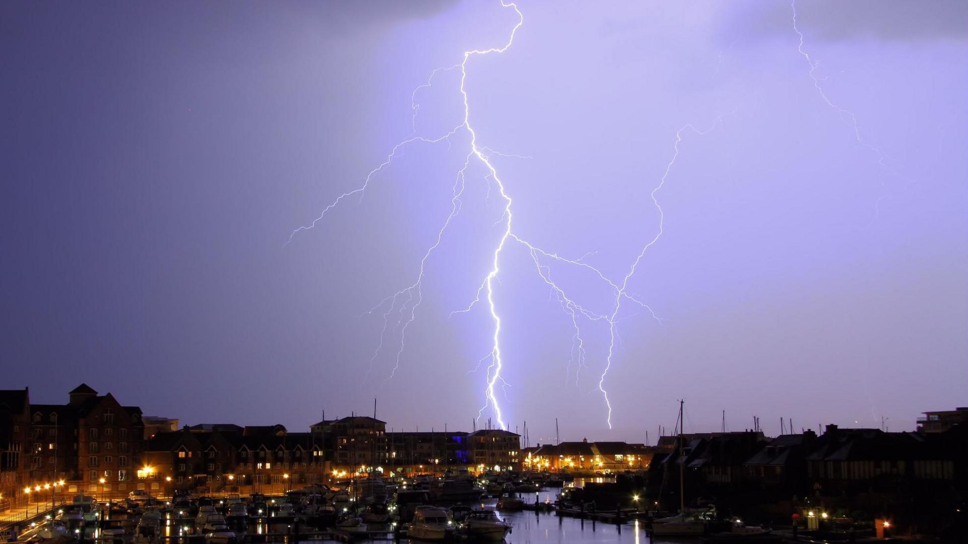 Lightning above a harbour on a purple background