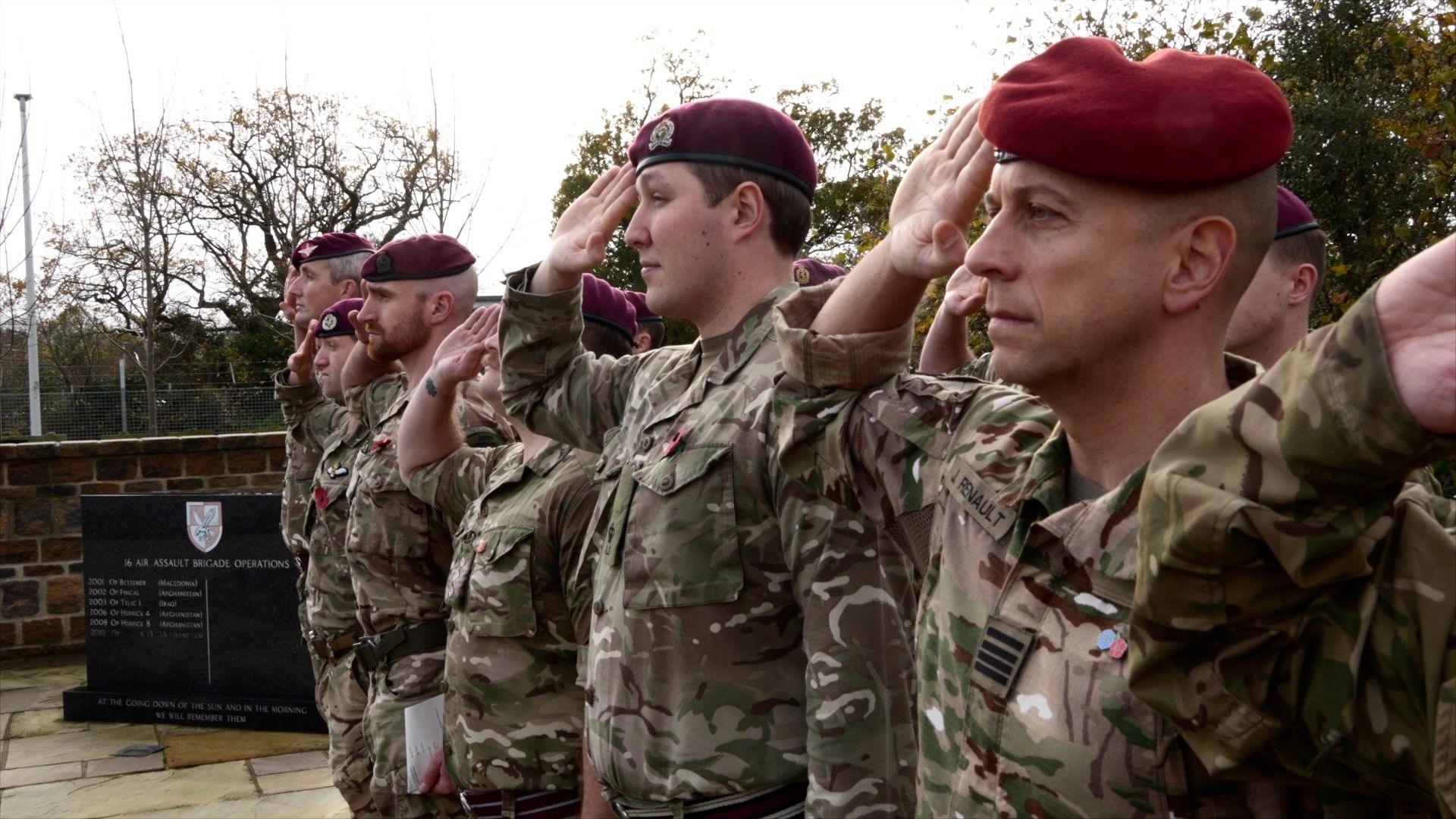 A row of army personnel in uniform standing in a line saluting at Merville Barracks in Colchester, Essex. 