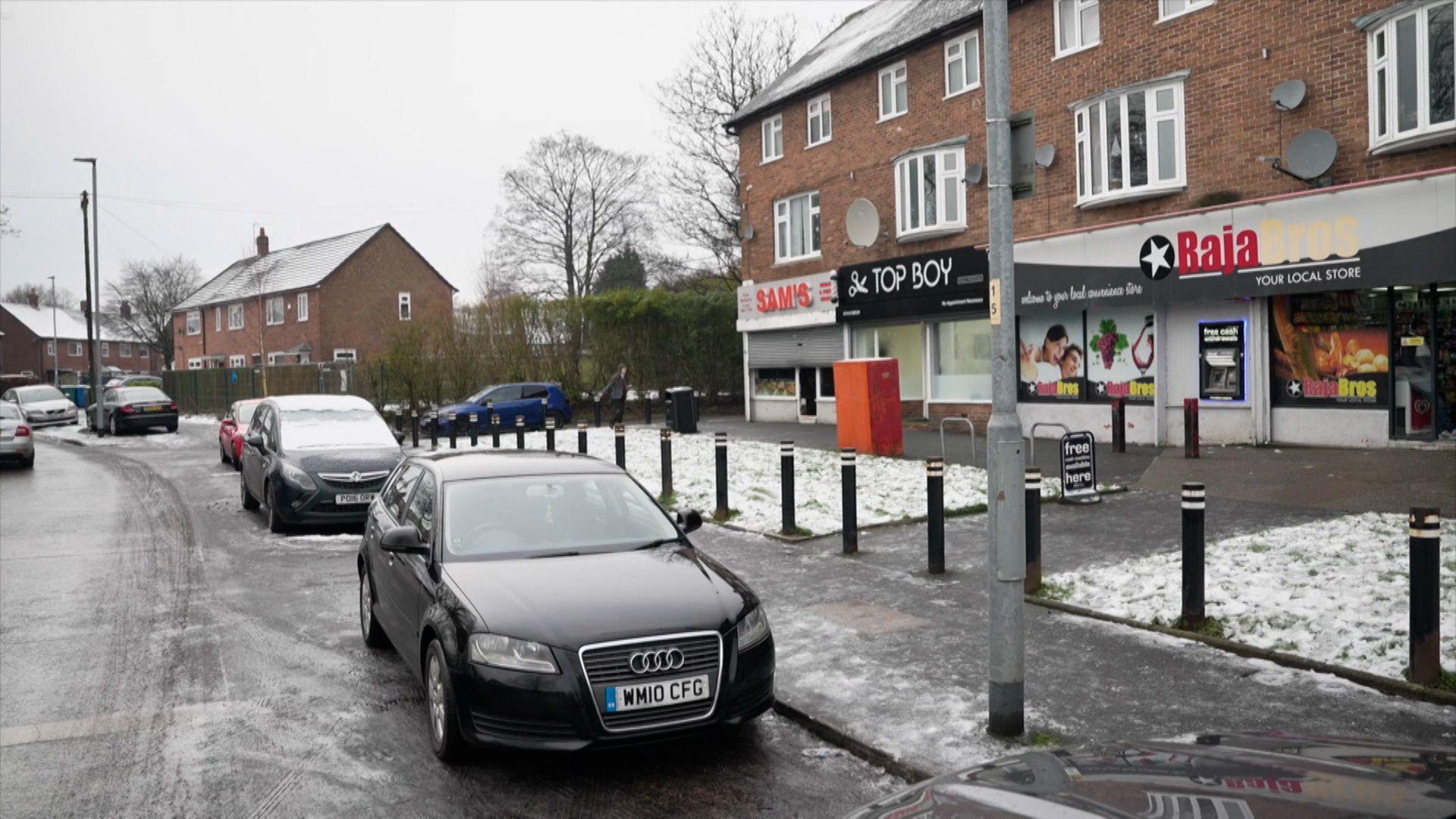 A row of shops including a takeaway, barbers and convenience shop on Button Lane in Wythenshawe, Manchester, in 2025.