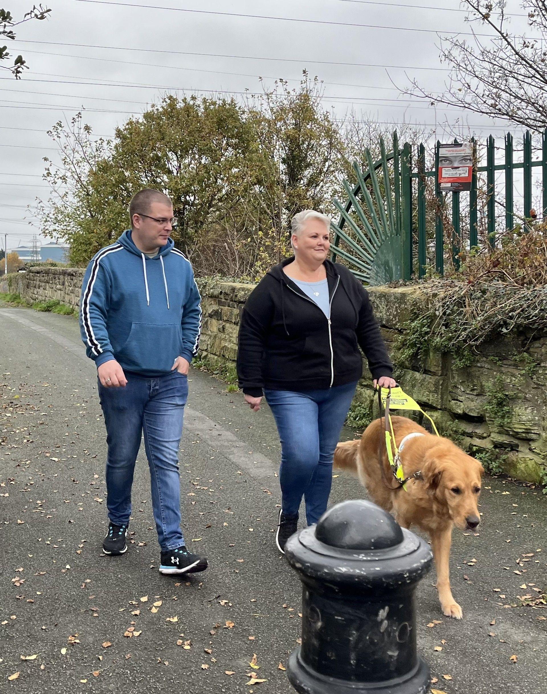 Man and woman walking with a guide dog