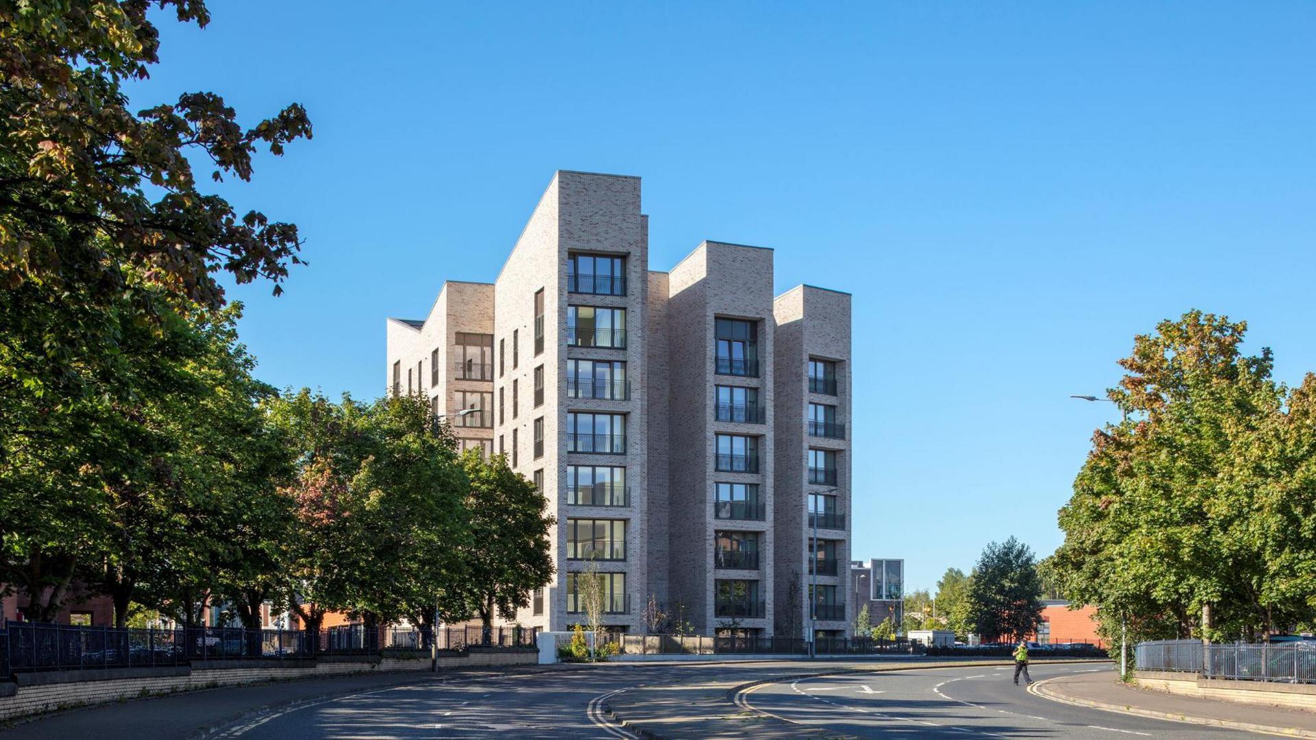 The front view of North Gate, a light coloured brick building. It has three "prongs", with apartments stacked eight high which have large windows