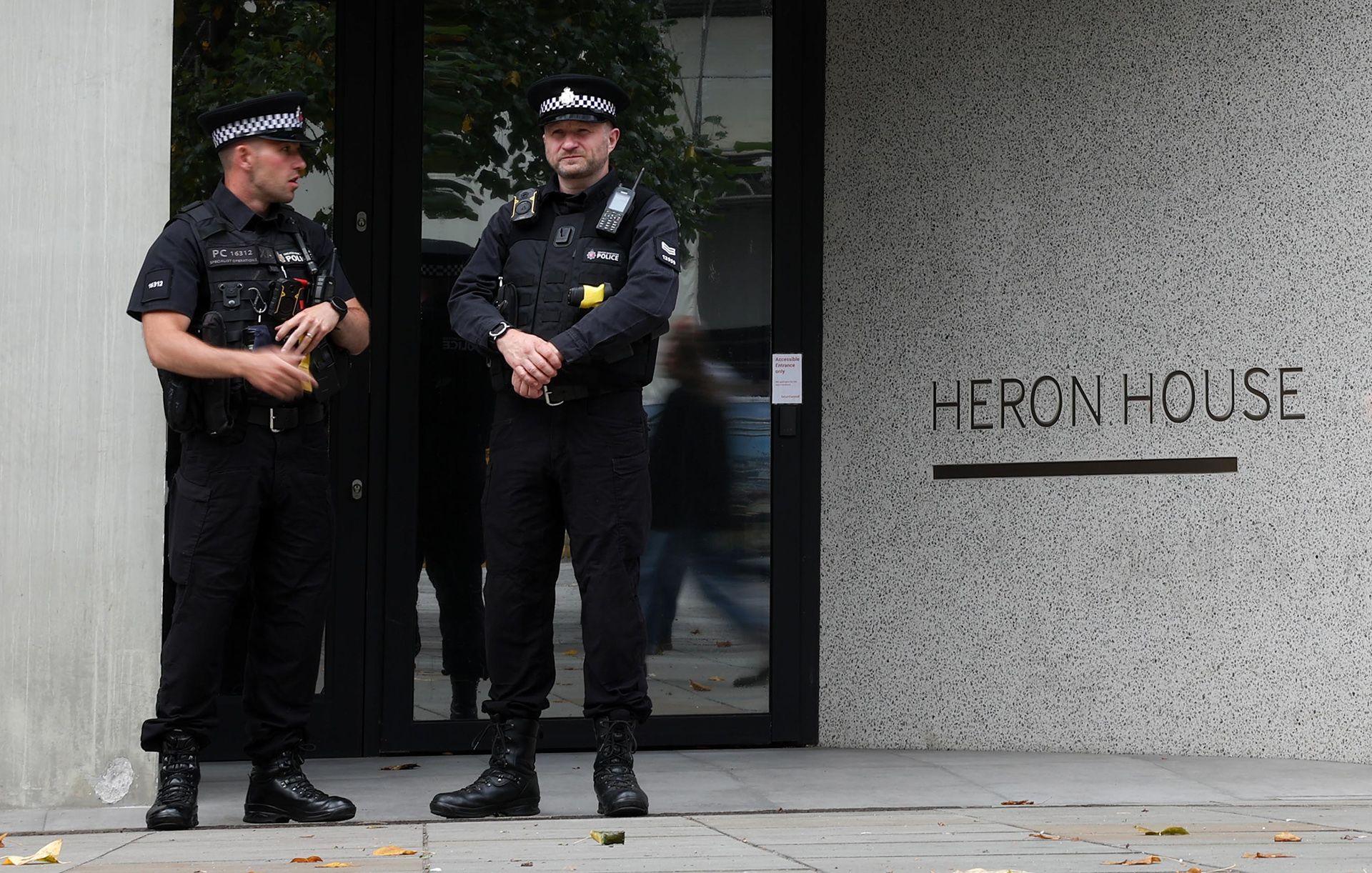 Two police officers stand in front of the entrance to a building with lettering that reads 'Heron House', in Manchester on 23 July.