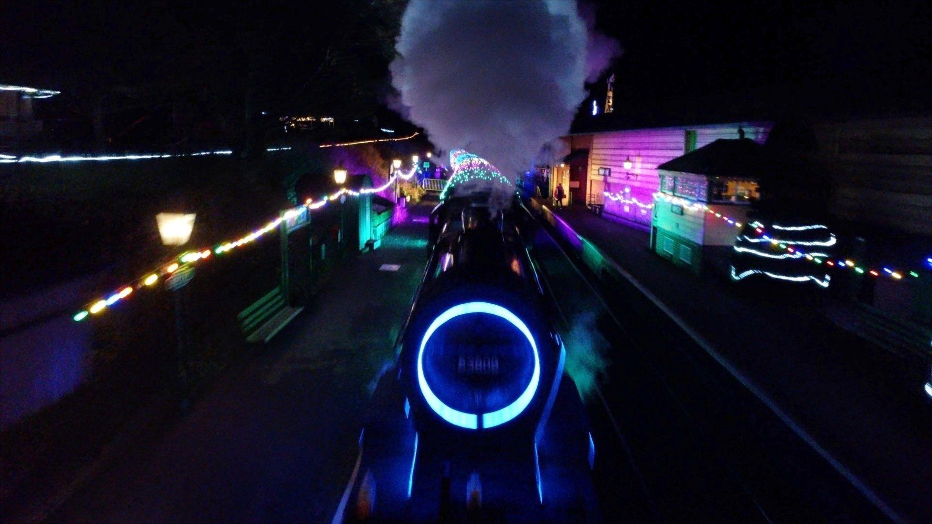 The front of an illuminated speed train racing along a track.