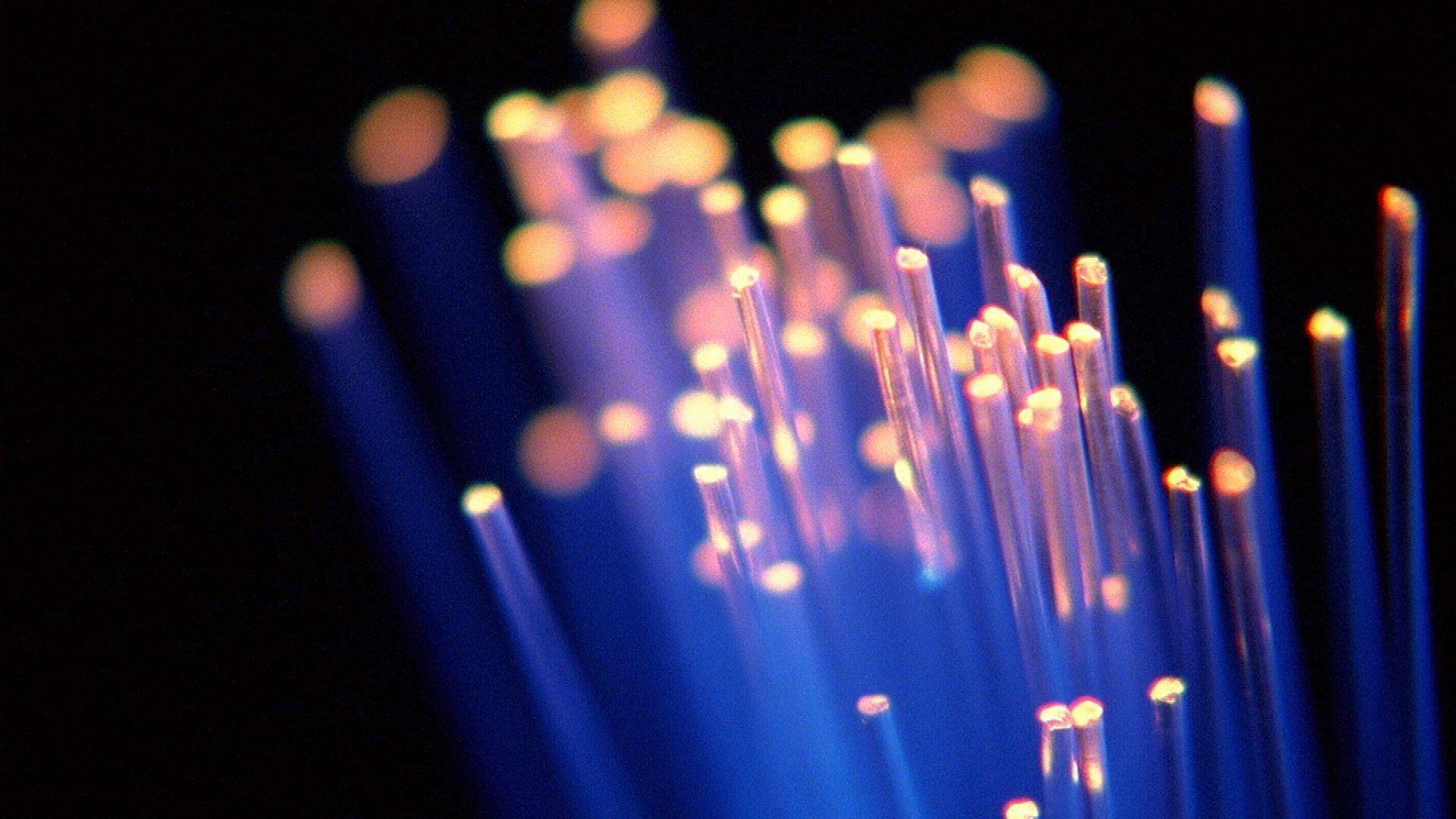 Strands of blue fibre optic cable light up in the dark with their ends shining with an orange glow