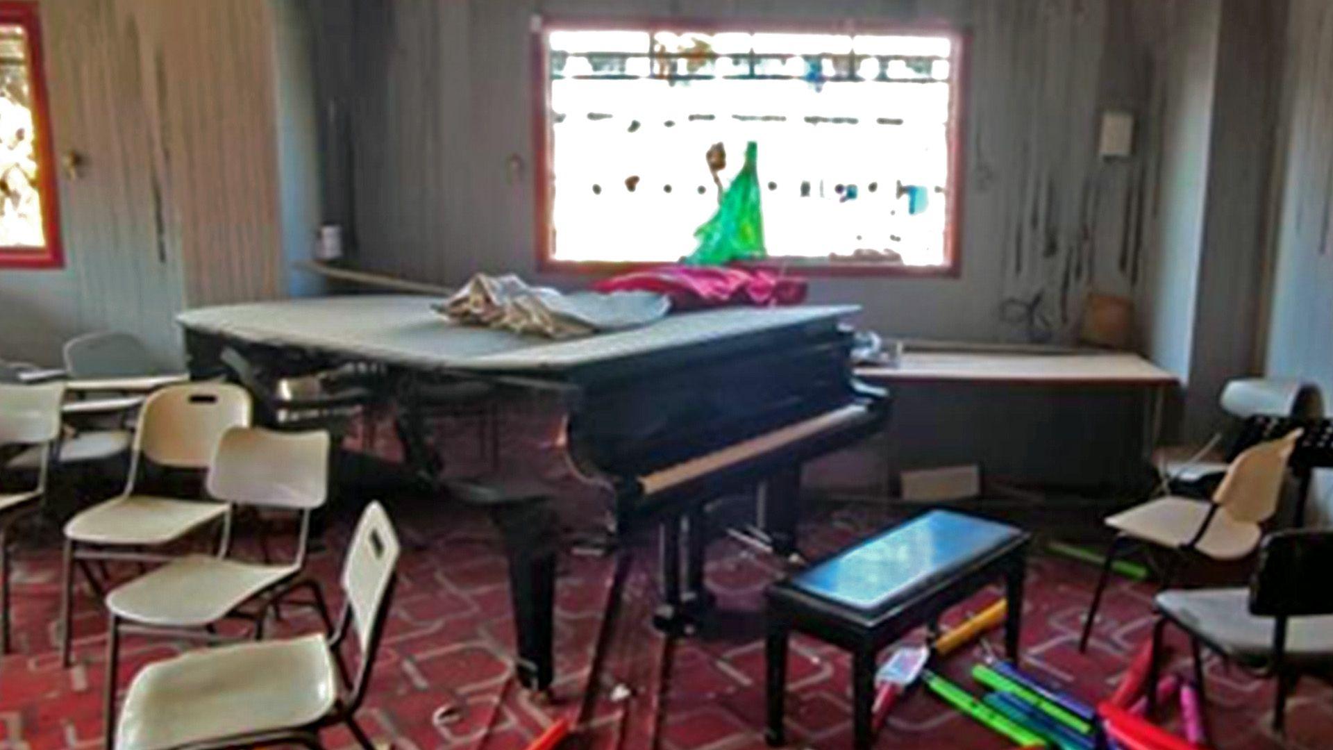 Gaza's only concert grand piano photographed in the Gaza branch of  the Palestinian music school, the Edward Said National Conservatory of Music,  late last year year. A dusty grand piano, with its top down, is surrounded by scattered plastic chairs, and lit by two stained glass windows