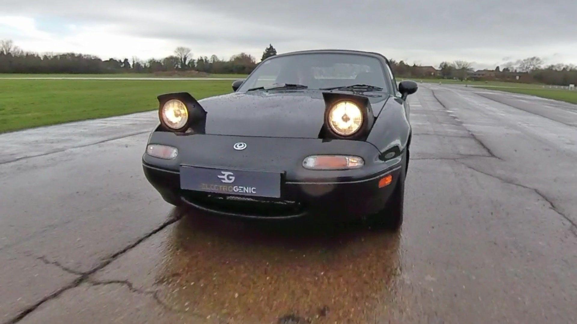 Mazda MX-5 in black with headlights up.