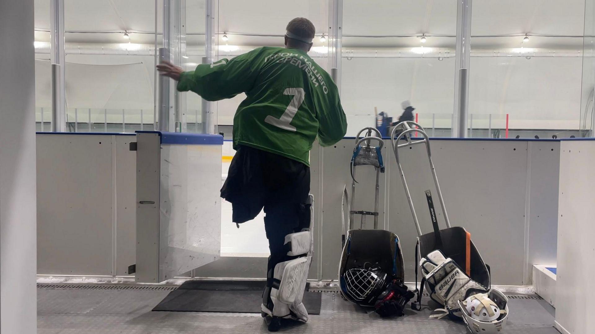 A Russian ice hockey player with one leg enters the ice rink, wearing pads and a green jersey