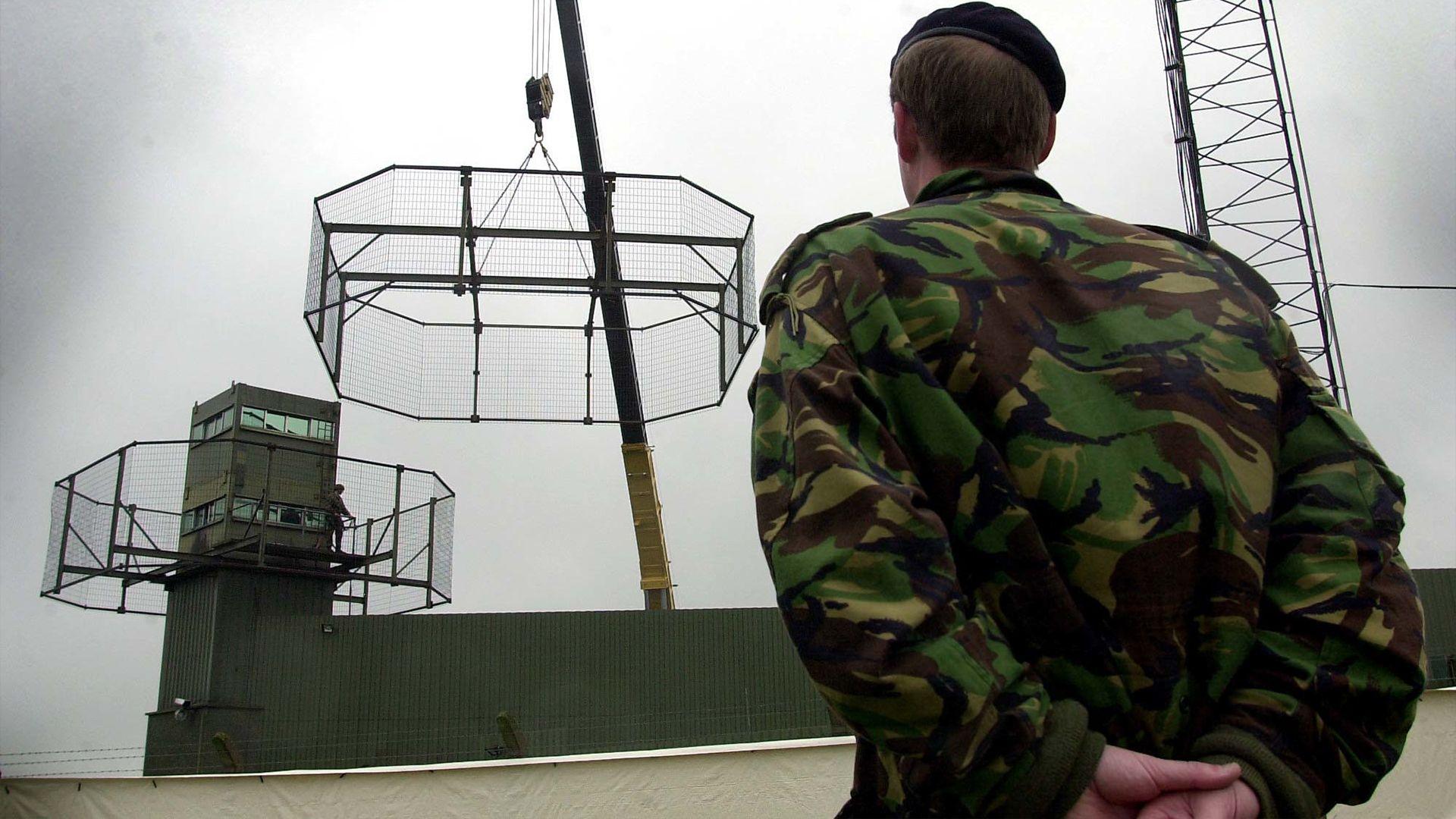 A uniformed soldier overlooks thee dismantling of Army observation towers in South Armagh.