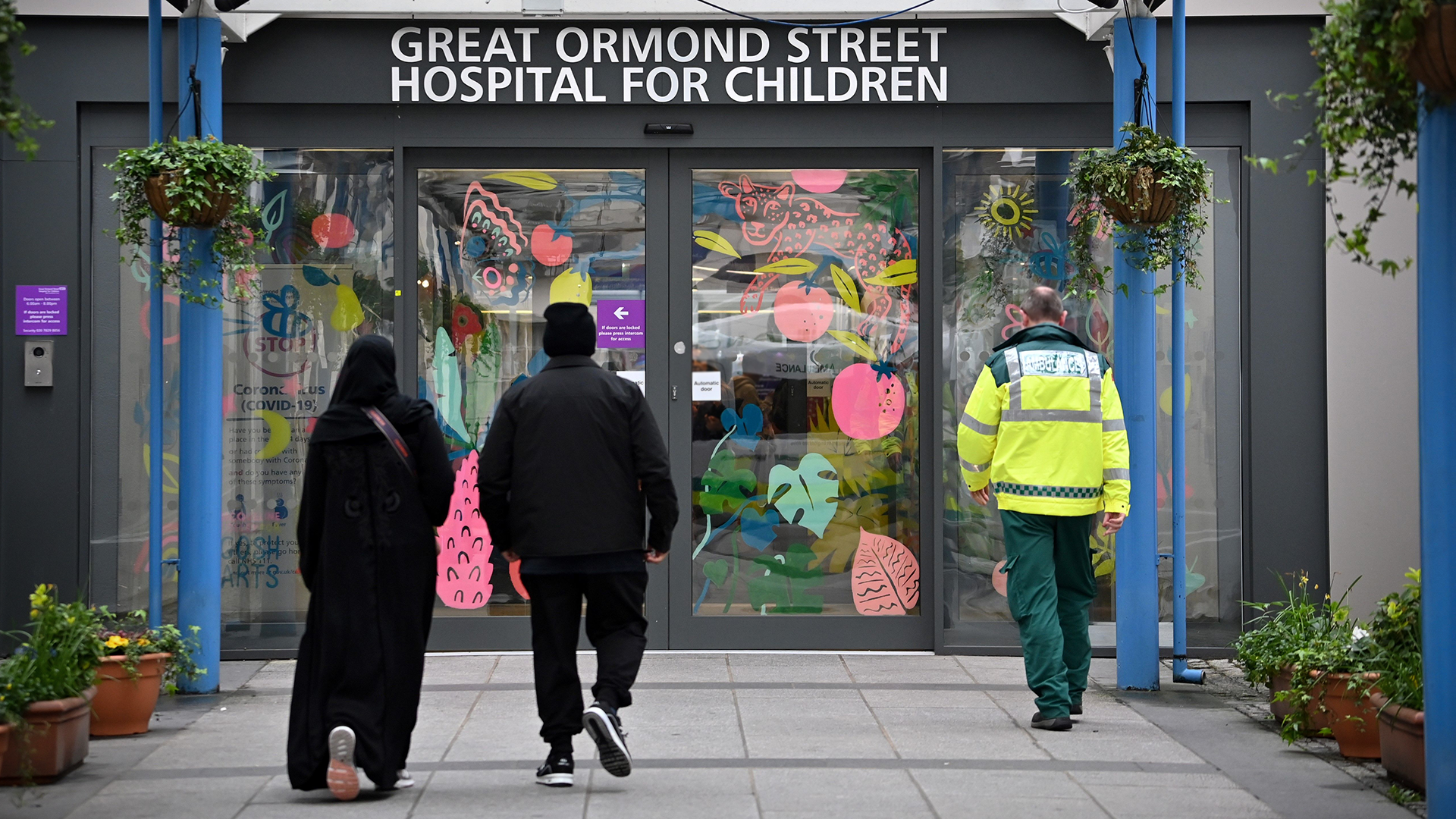 People walk under a sign for Great Ormond Street Hospital at its entrance