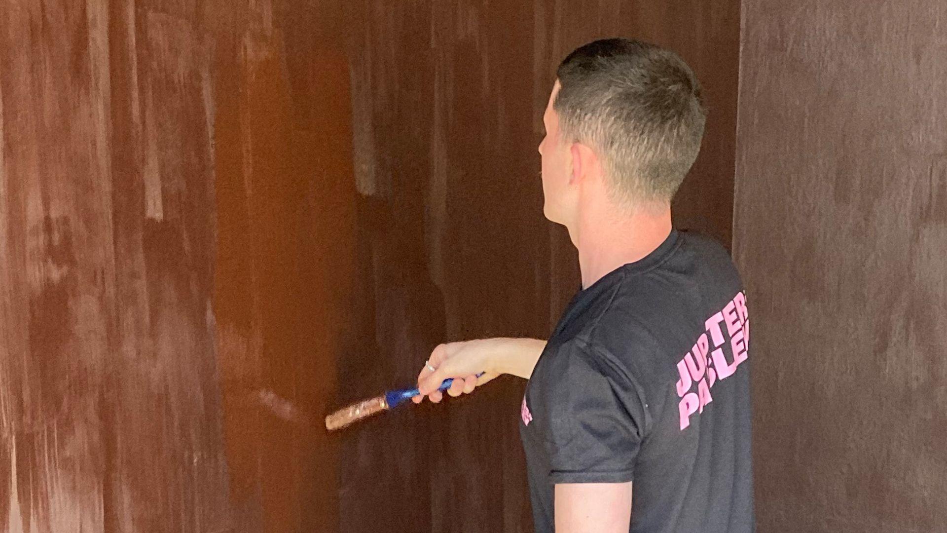 A person paints a wall in chocolate coloured paint