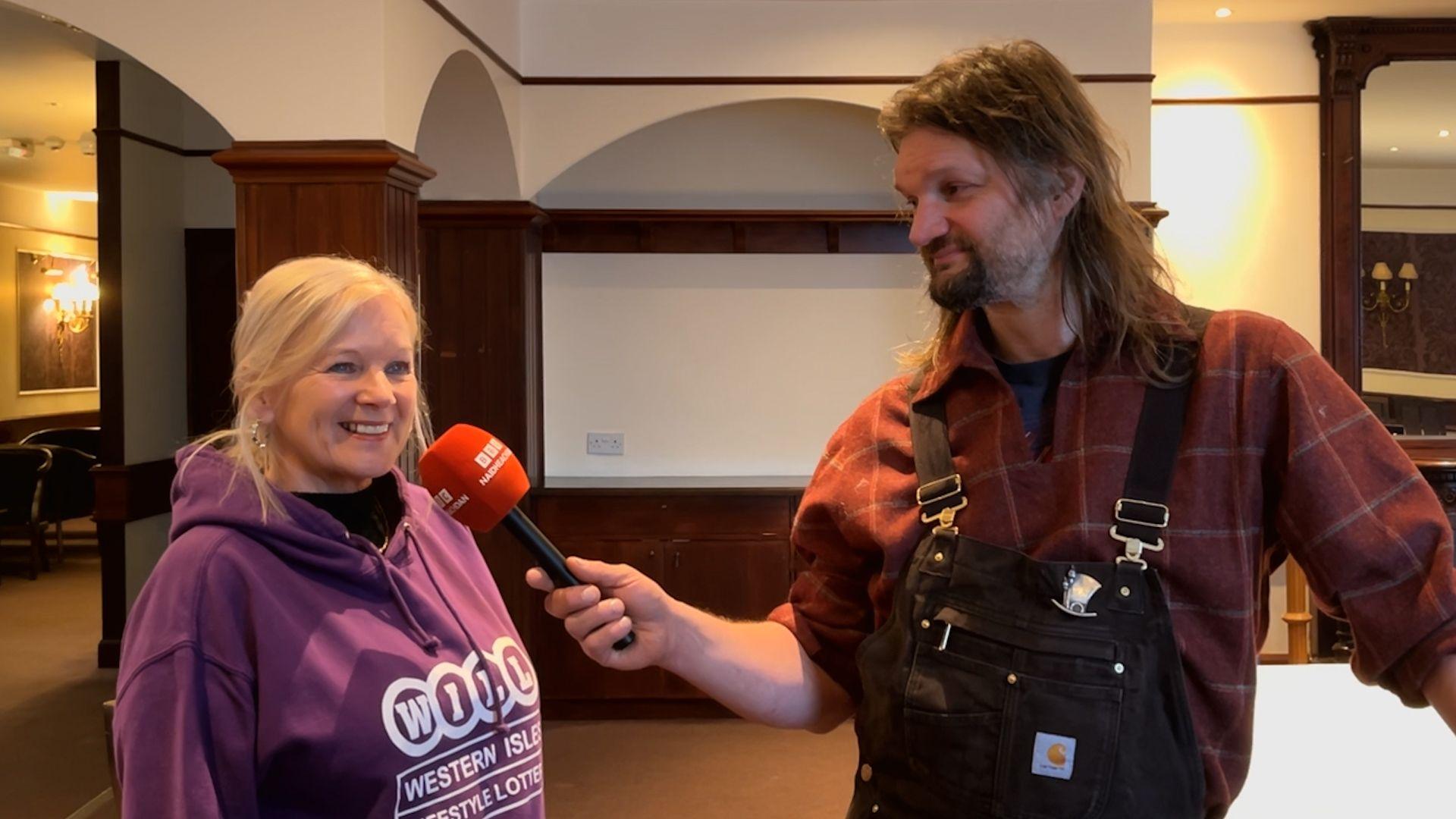 Janet Paterson bho Crannchar nan Eilean Siar agus Chris Rutterford, an neach-ealain a chruthaich an dealbh-balla - an dithis aca a' coimhead toilichte agus iad an teis-mheadhan agallaimh.